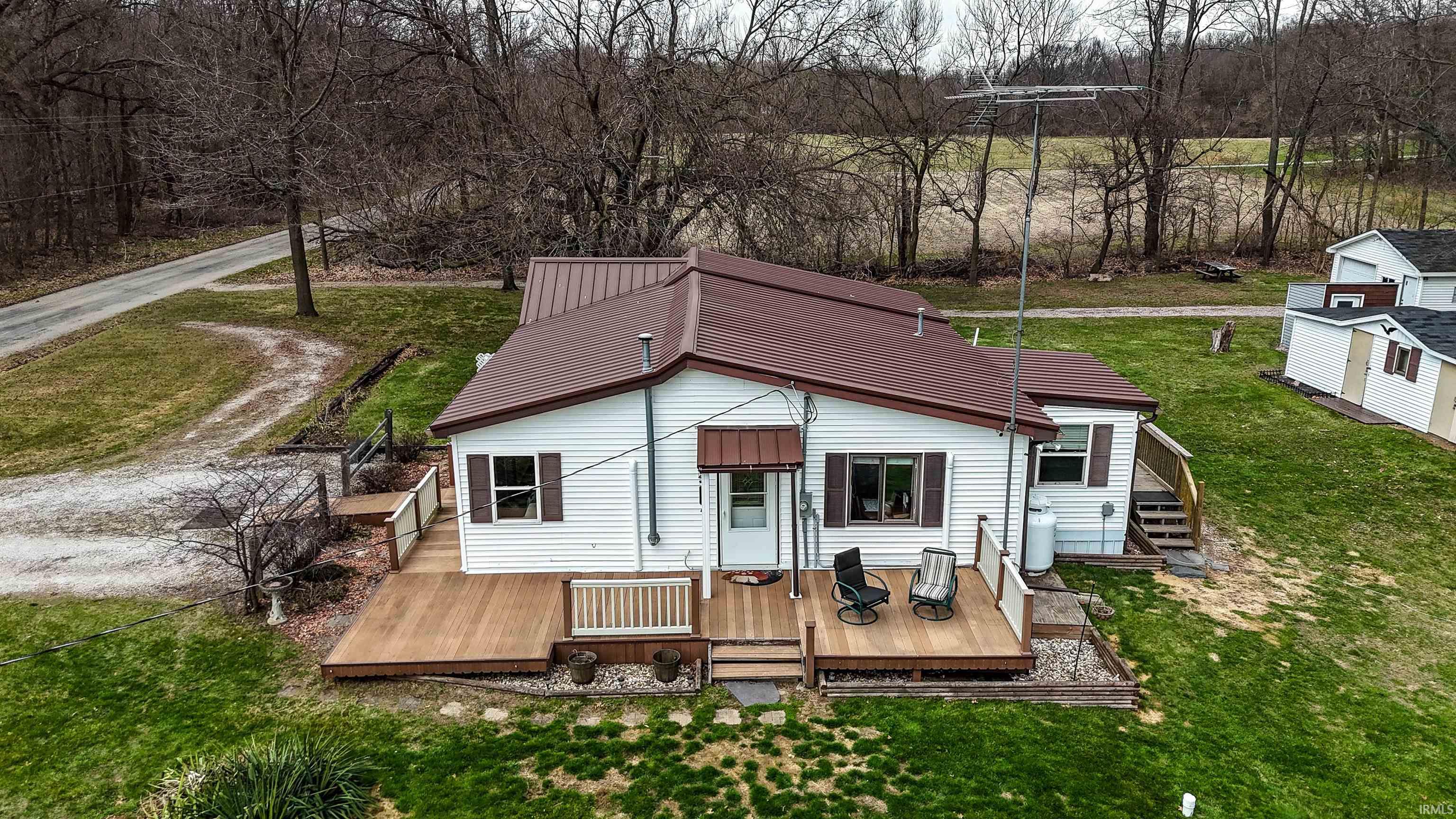 Rear view of property featuring a deck, a lawn, and a metal roof
