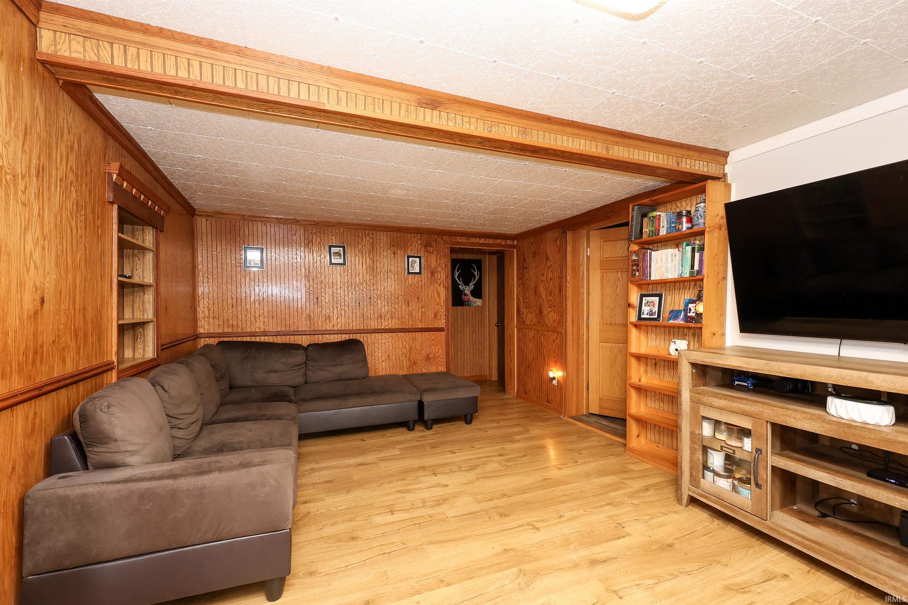 Living room featuring built in shelves, wood walls, and wood finished floors