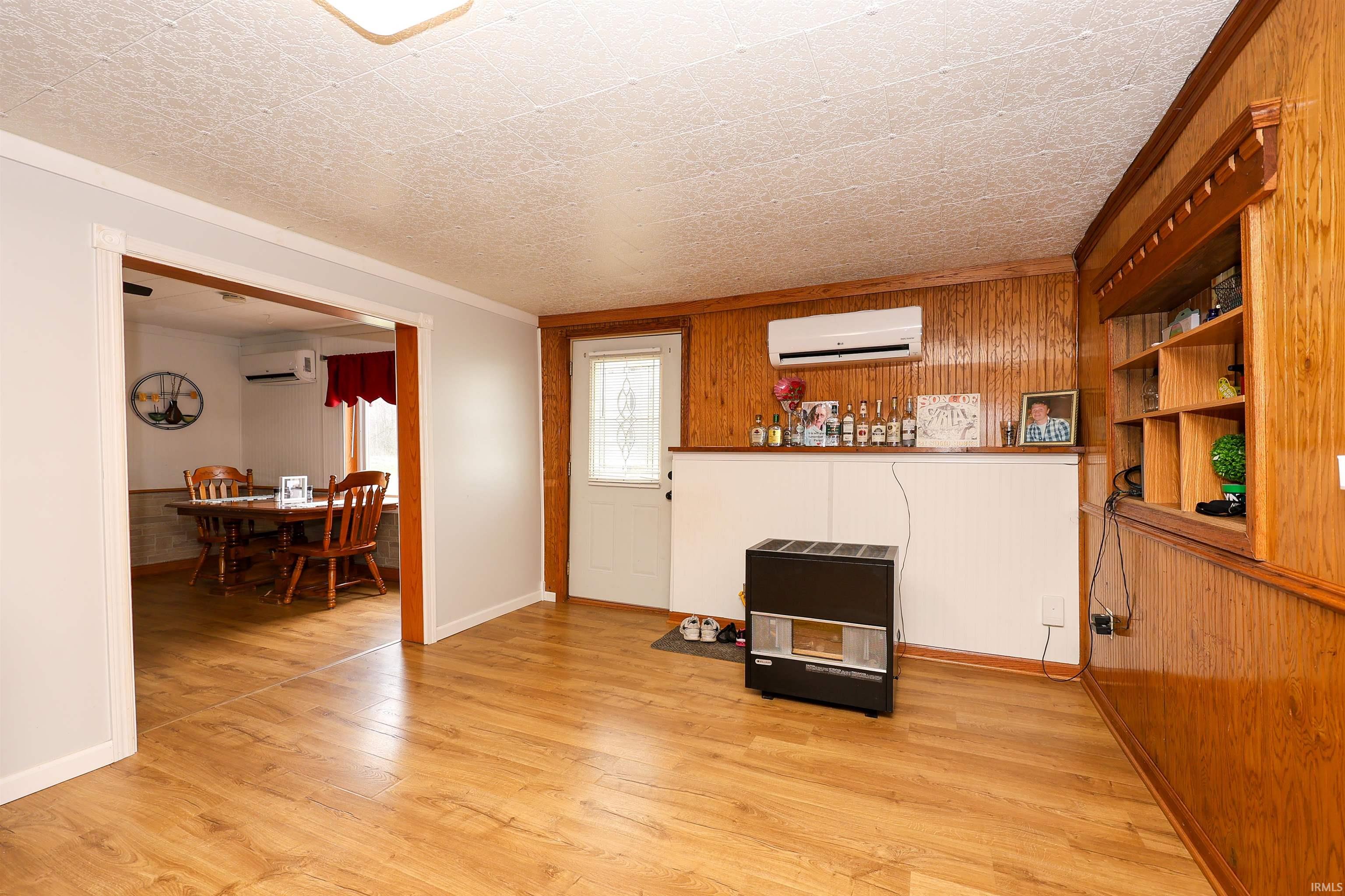 Living area featuring light wood finished floors, crown molding, and wood walls