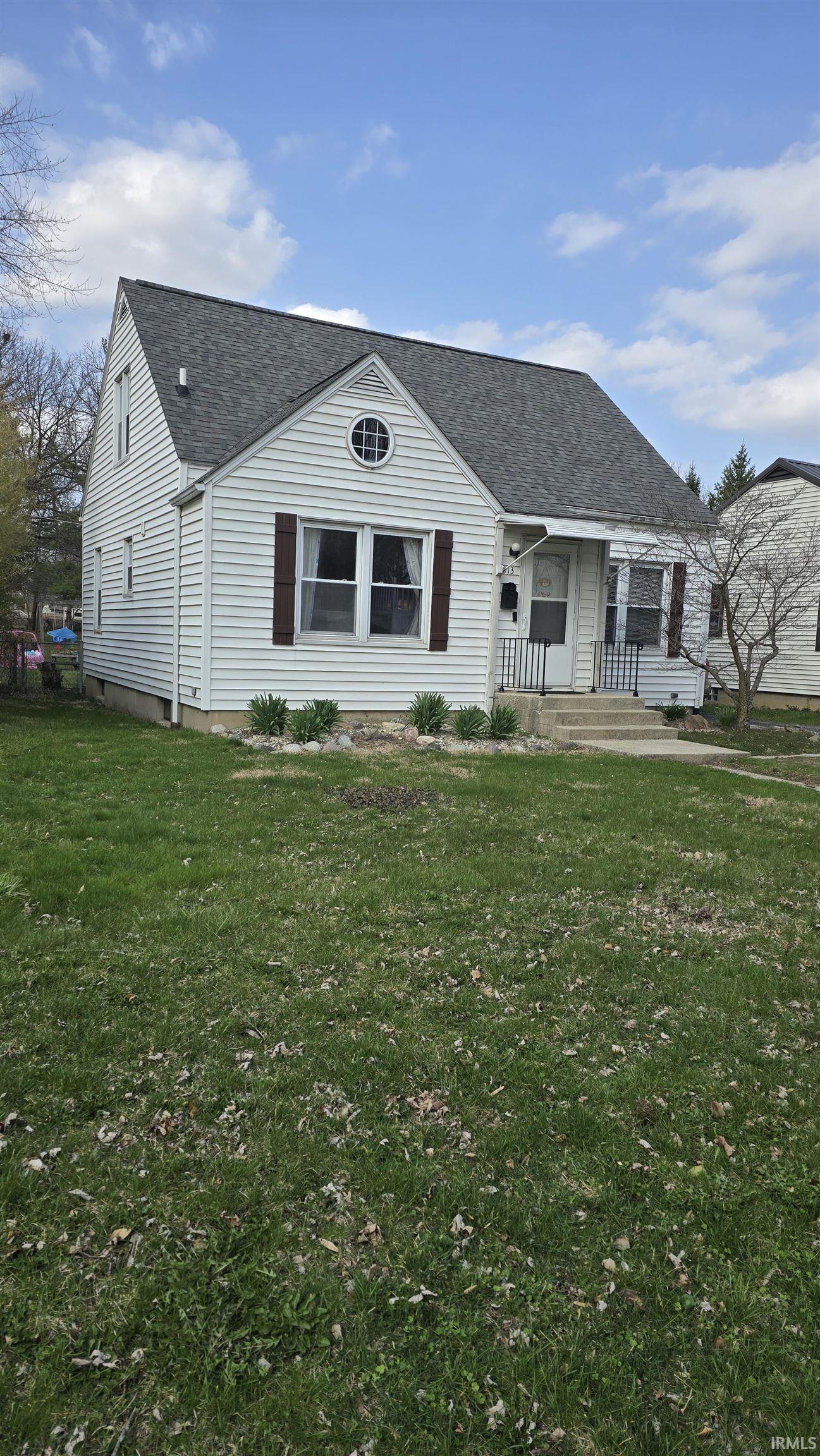 View of front of property featuring roof with shingles, a front lawn, and covered porch