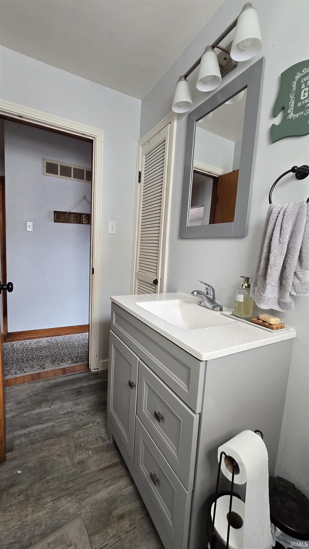 Half bath with vanity and dark wood-type flooring