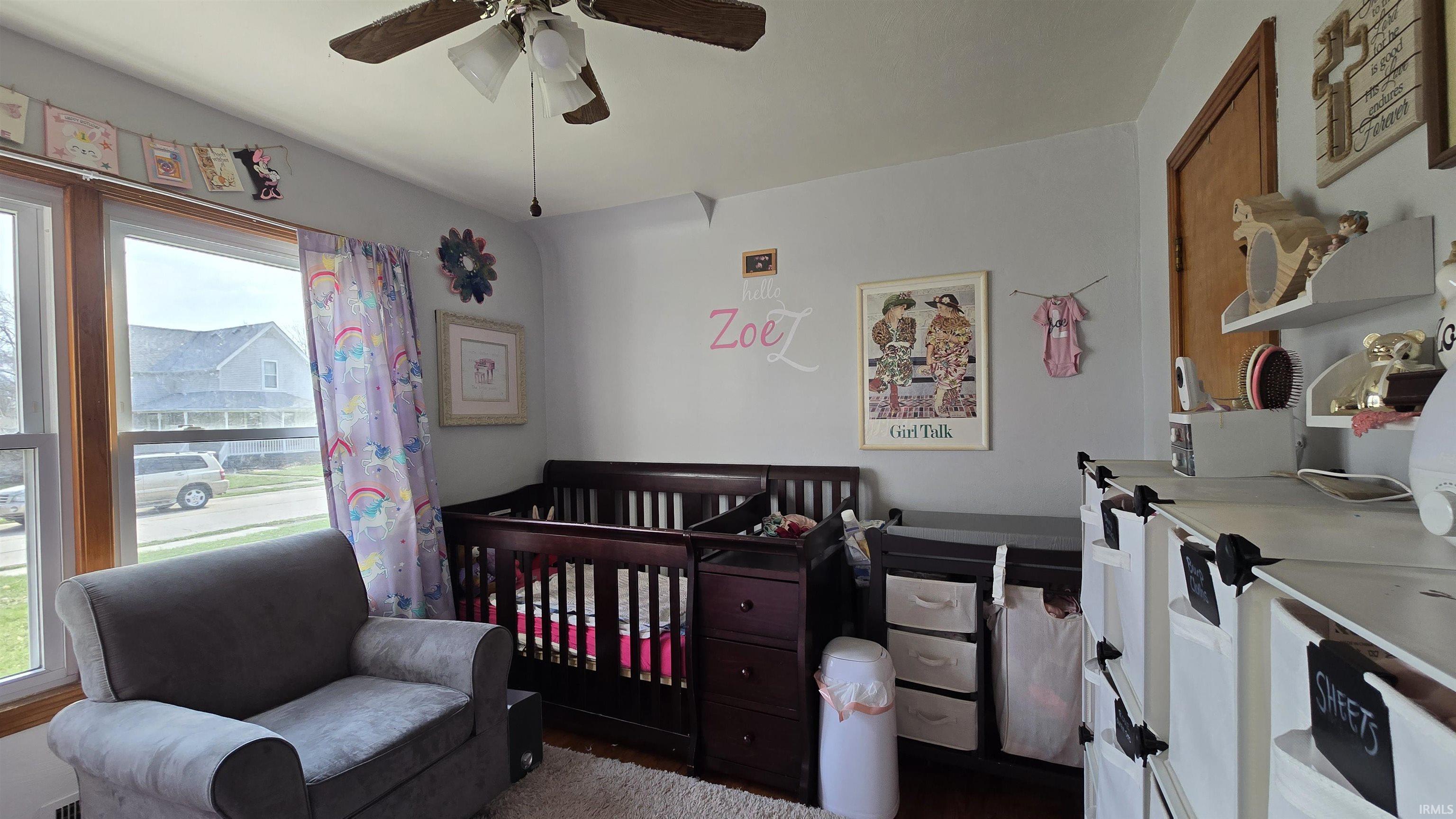 Bedroom with a ceiling fan and a crib