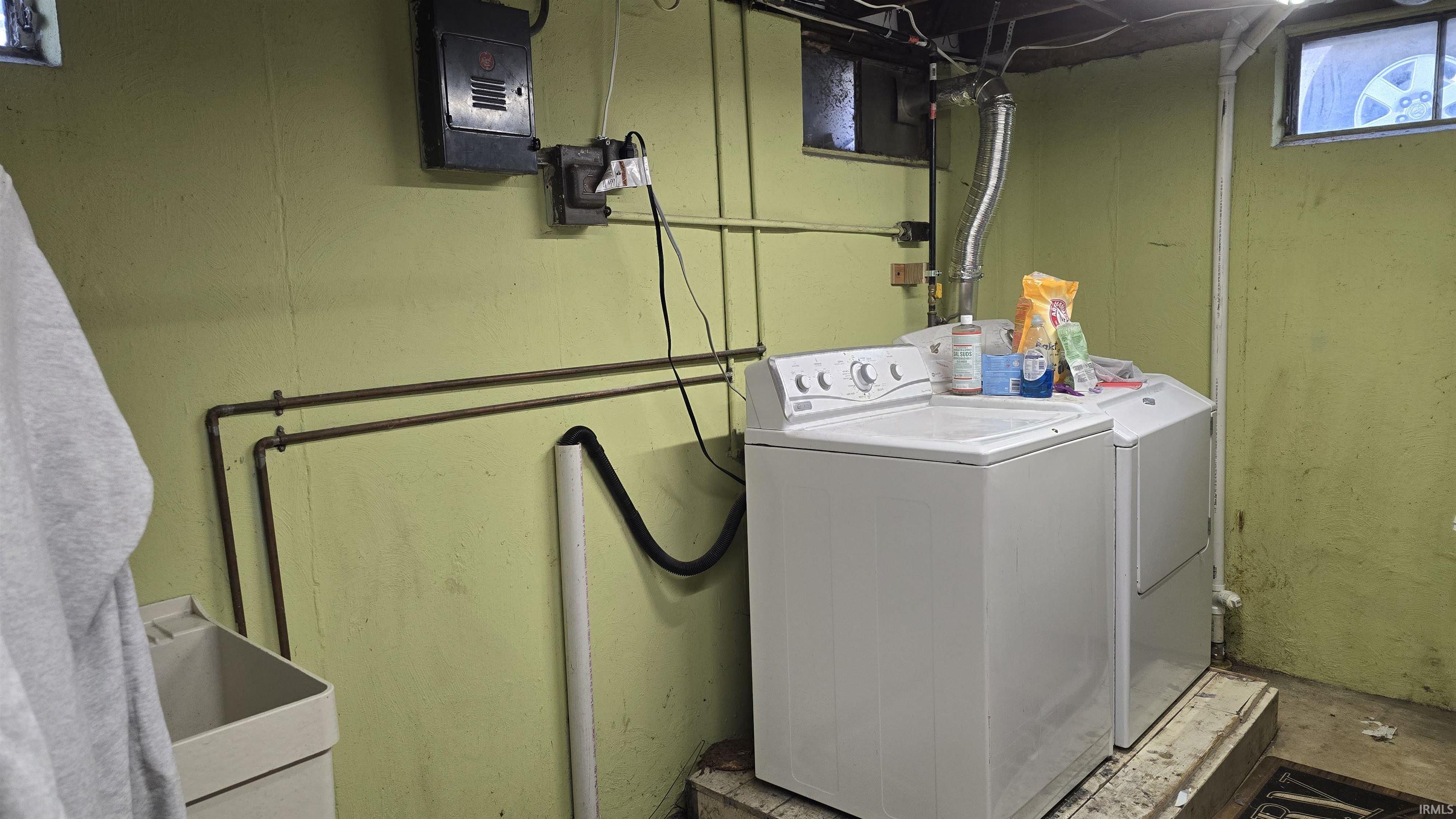 Laundry area with washer and dryer, concrete flooring, and electric panel
