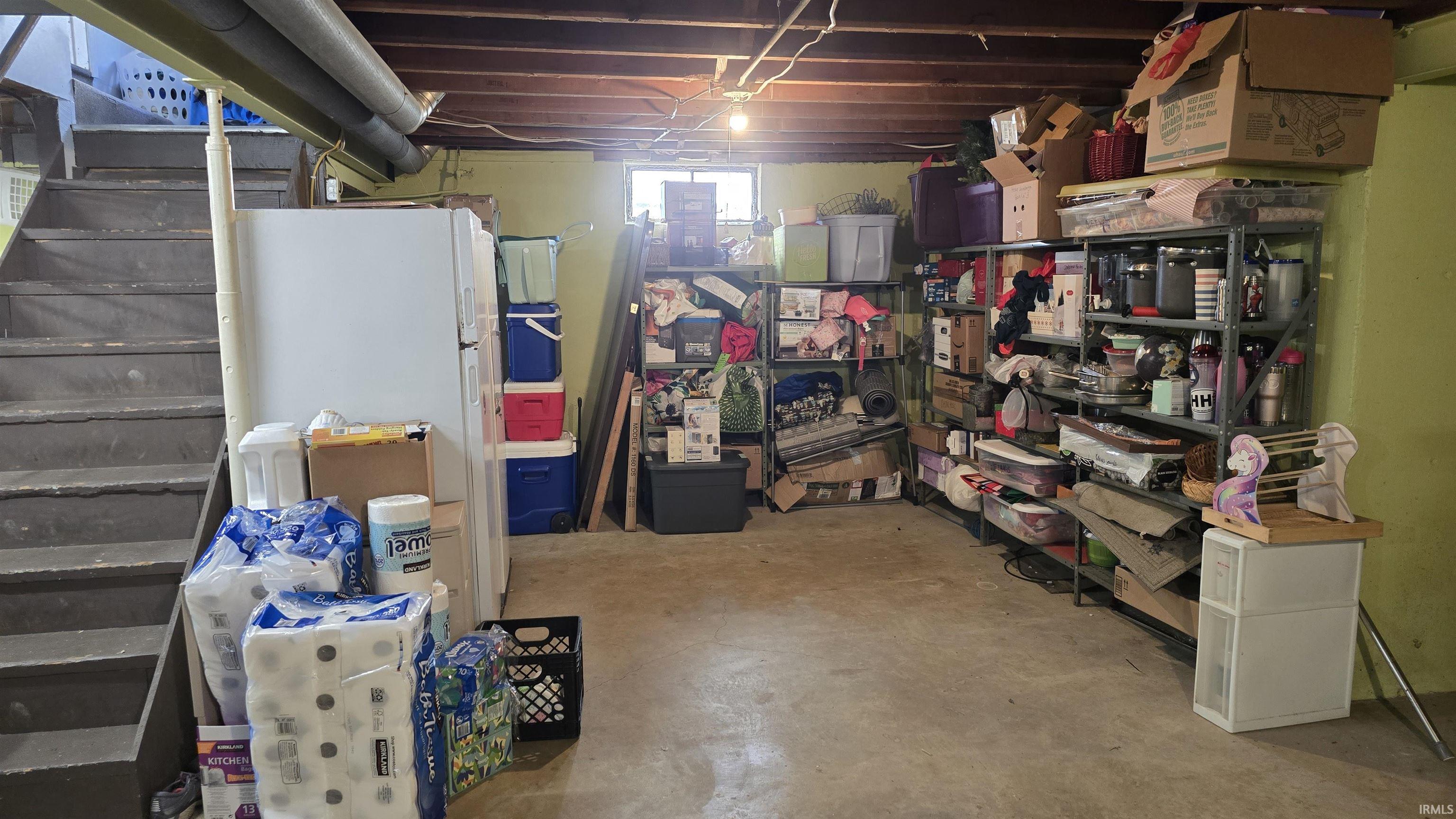 Basement featuring stairs and freestanding refrigerator