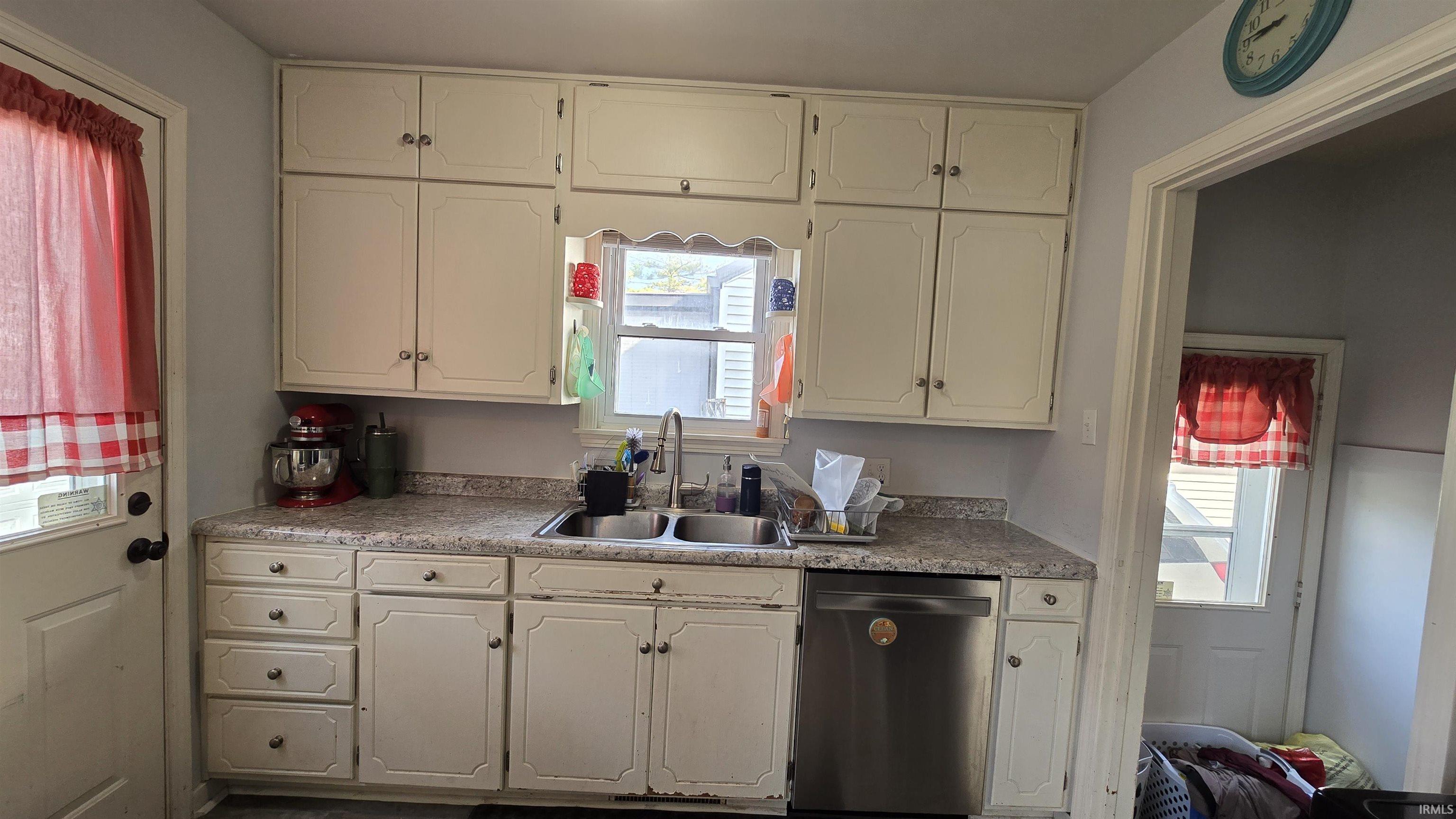 Kitchen featuring dishwasher, white cabinetry, and light countertops