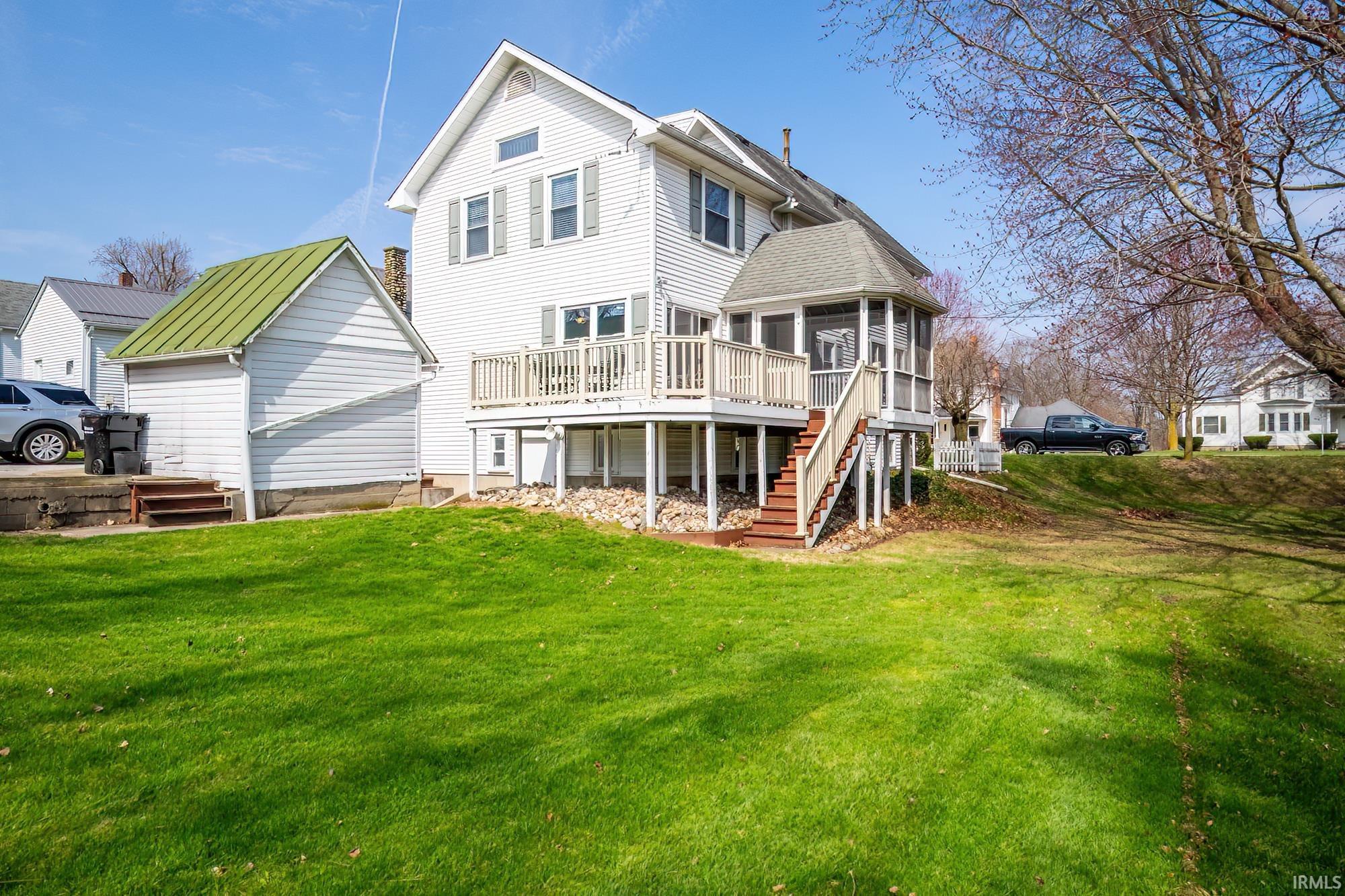 Rear view of house featuring a composite deck, a residential view, a yard, and a sunroom