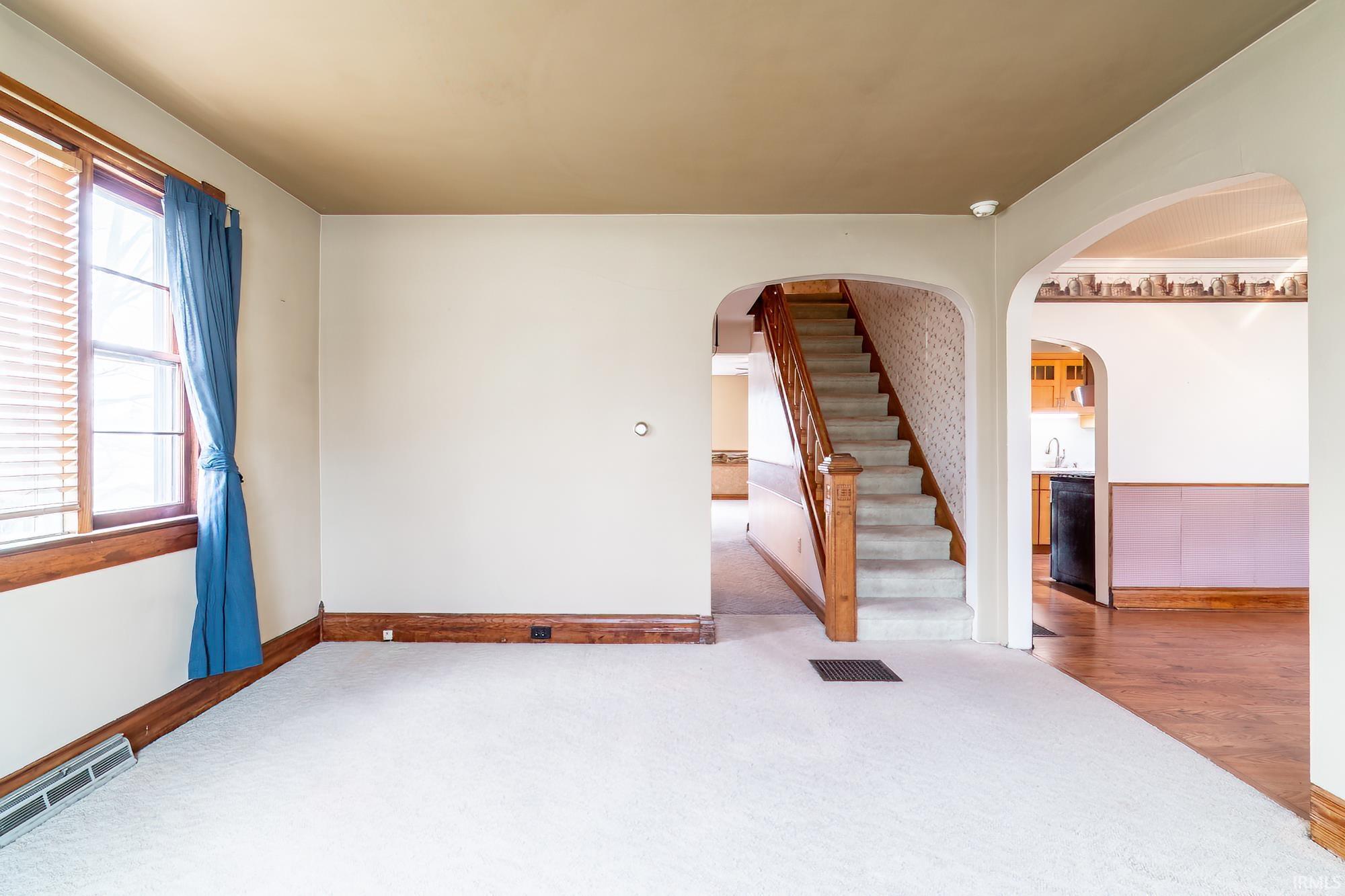 Empty room featuring stairway and carpet floors