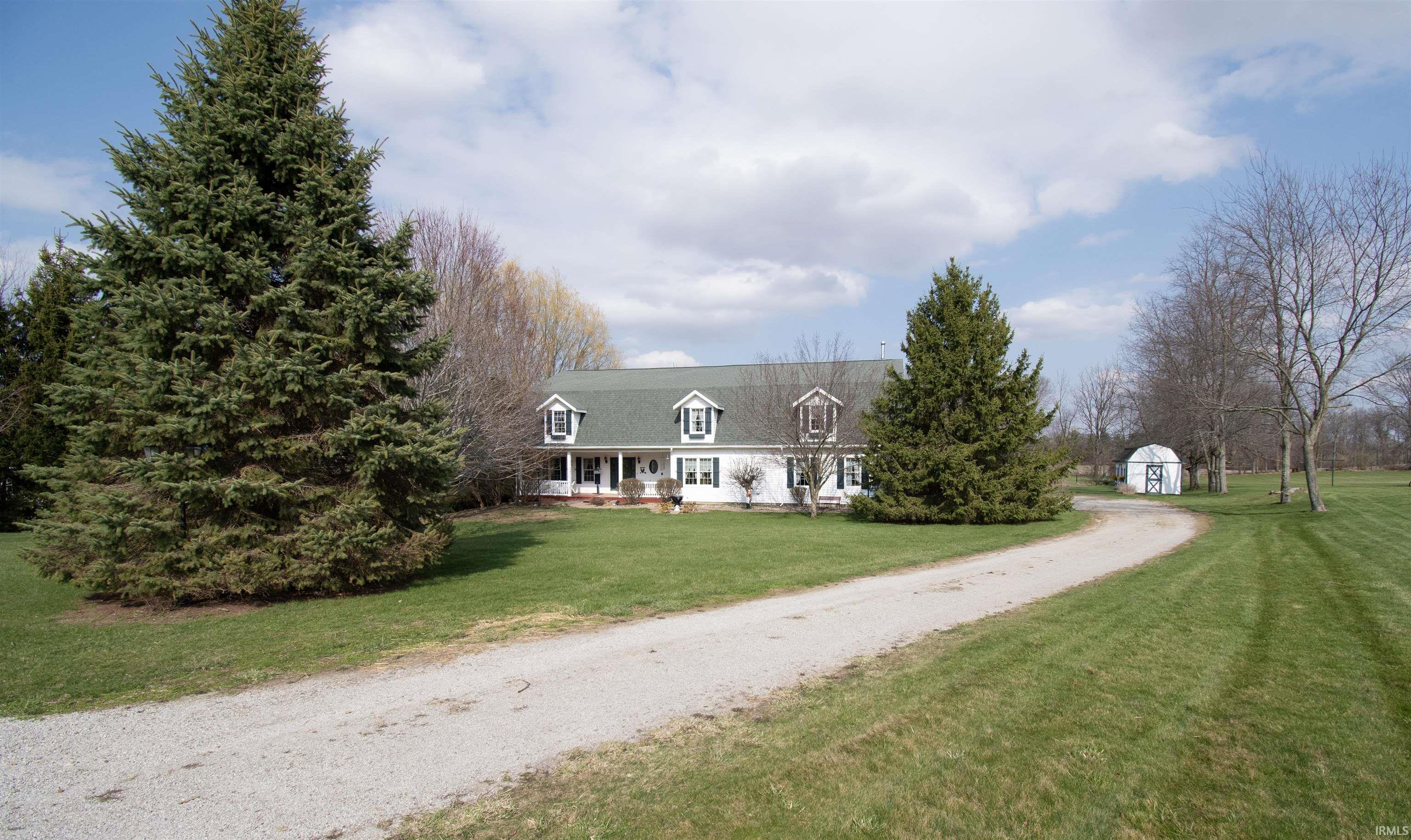 View of front of home with a porch, a front yard, dirt driveway, and a storage unit