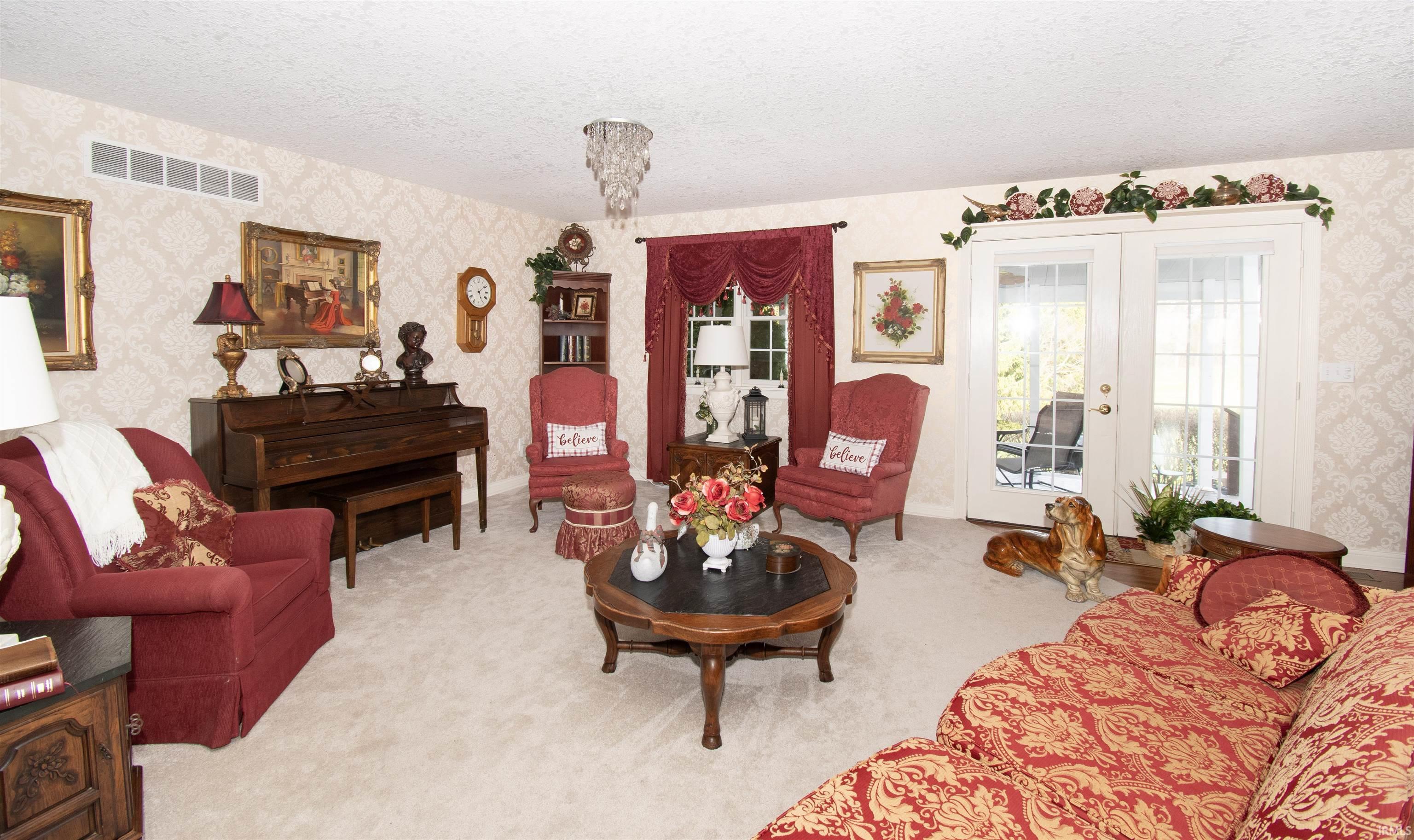 Living room with wallpapered walls, a textured ceiling, light carpet, and french doors