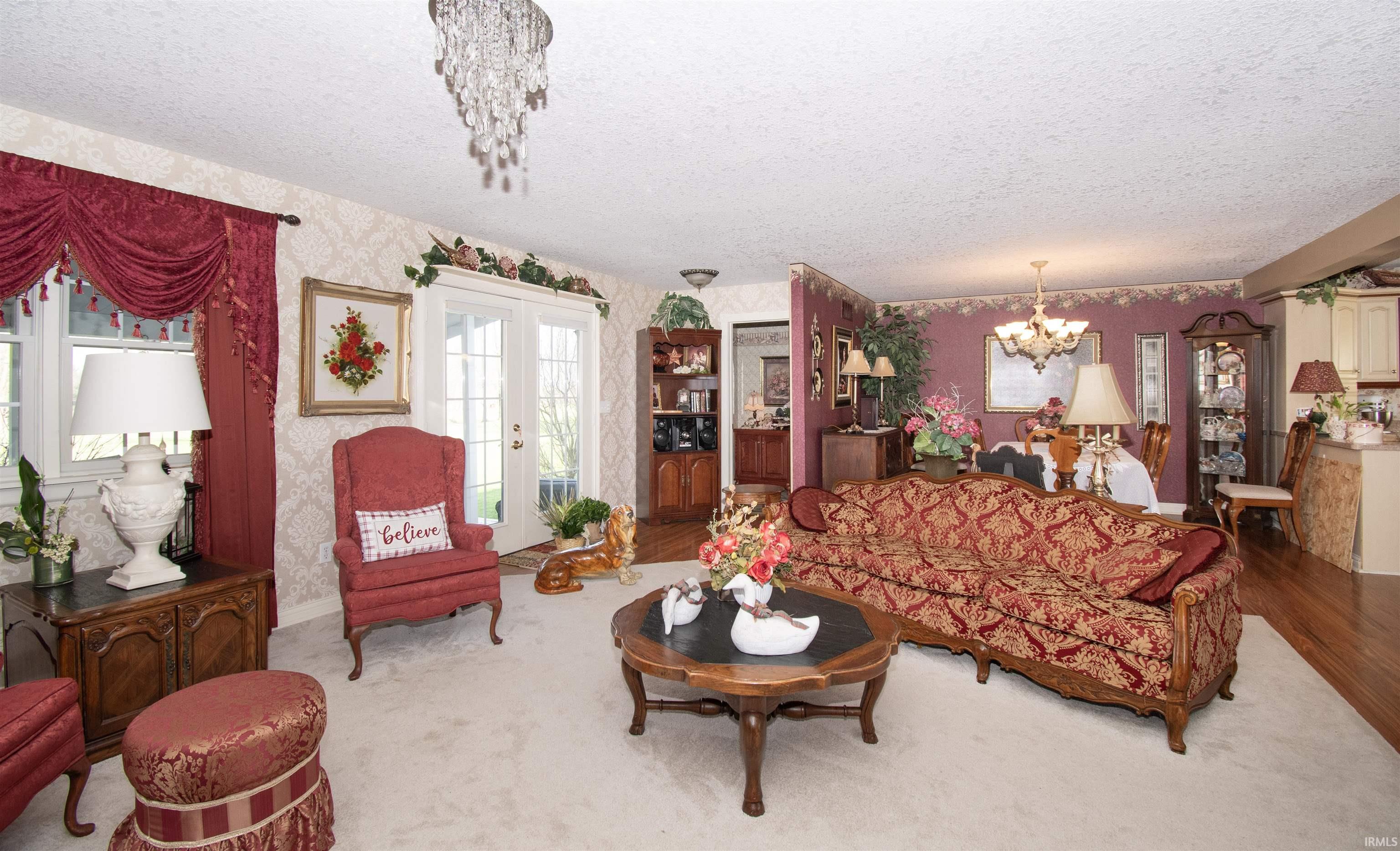 Living area featuring hanging lights, a textured ceiling, wallpapered walls, and french doors