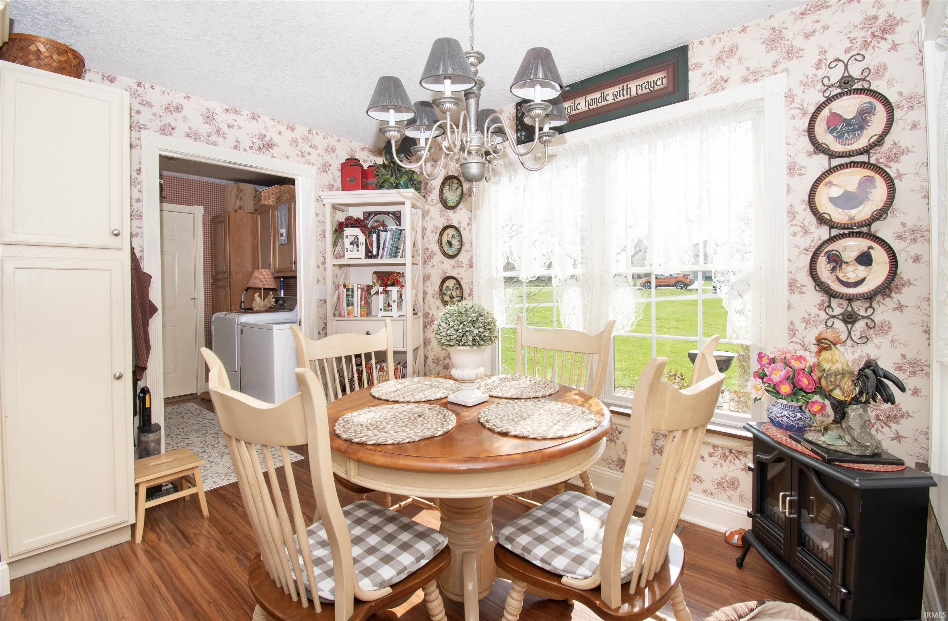 Dining space with wallpapered walls, suspended lighting, wood finished floors, and a textured ceiling