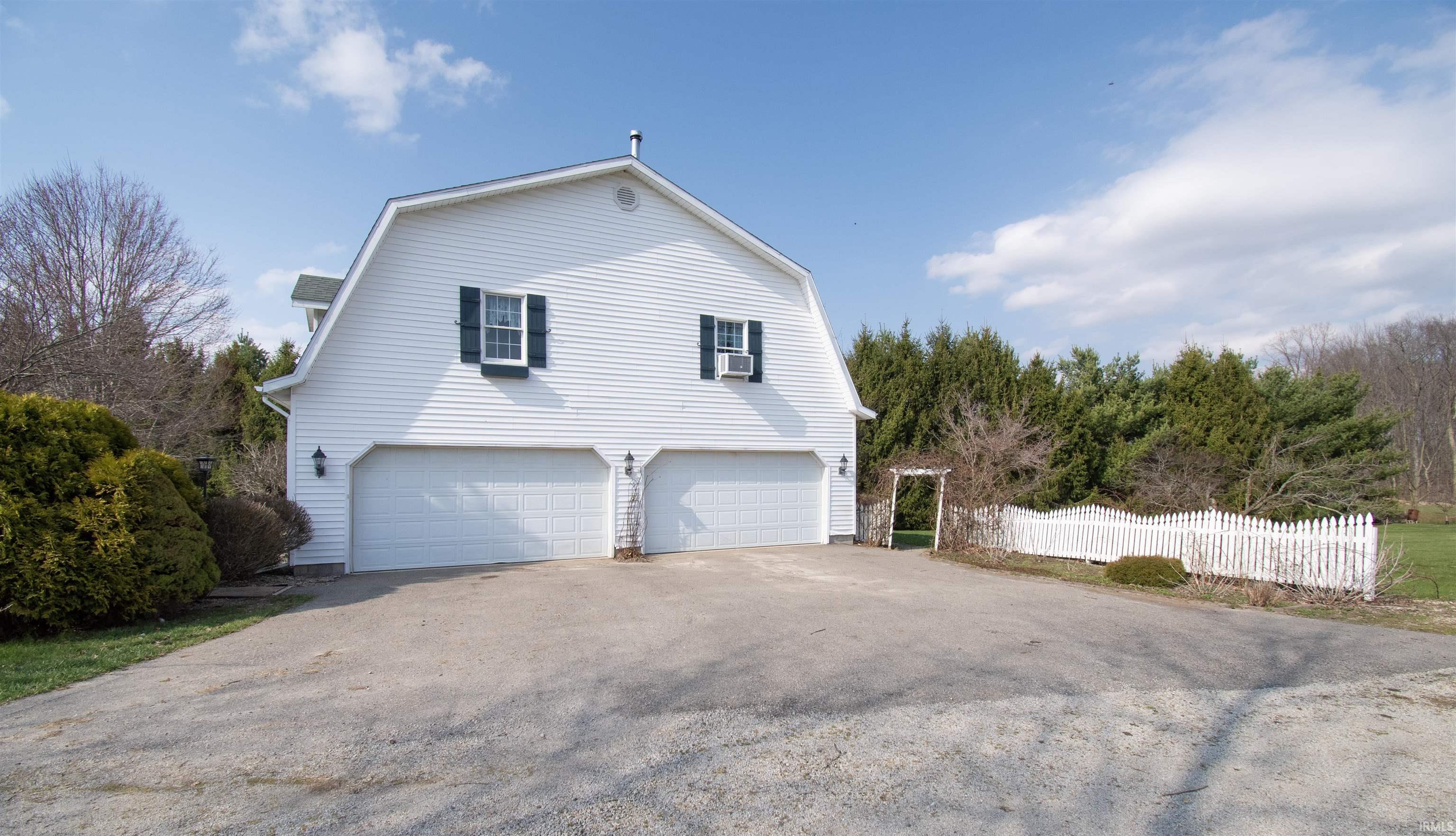 View of side of property featuring a gambrel roof, asphalt driveway, and a garage