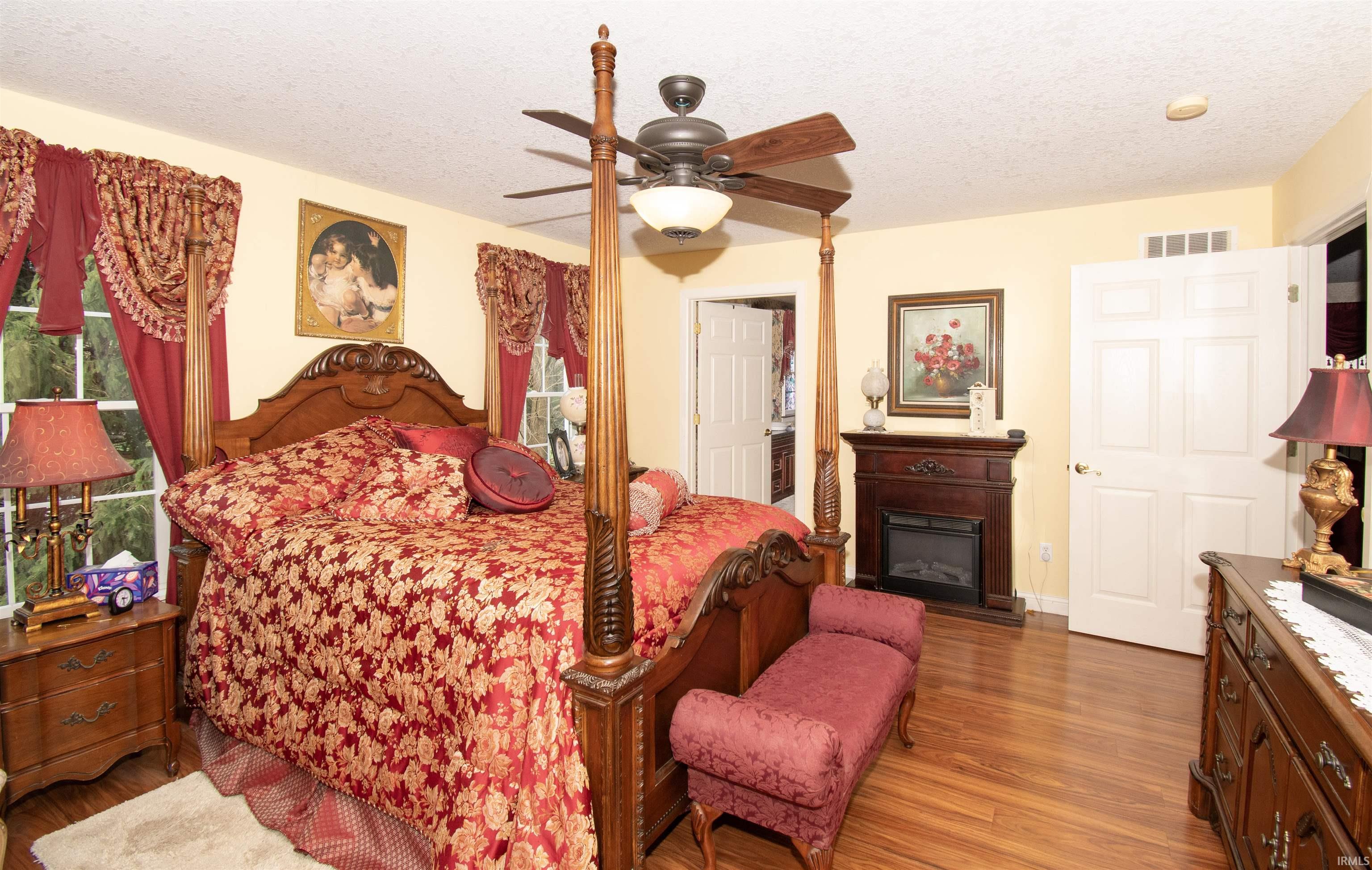 Bedroom with a textured ceiling, wood finished floors, and a ceiling fan