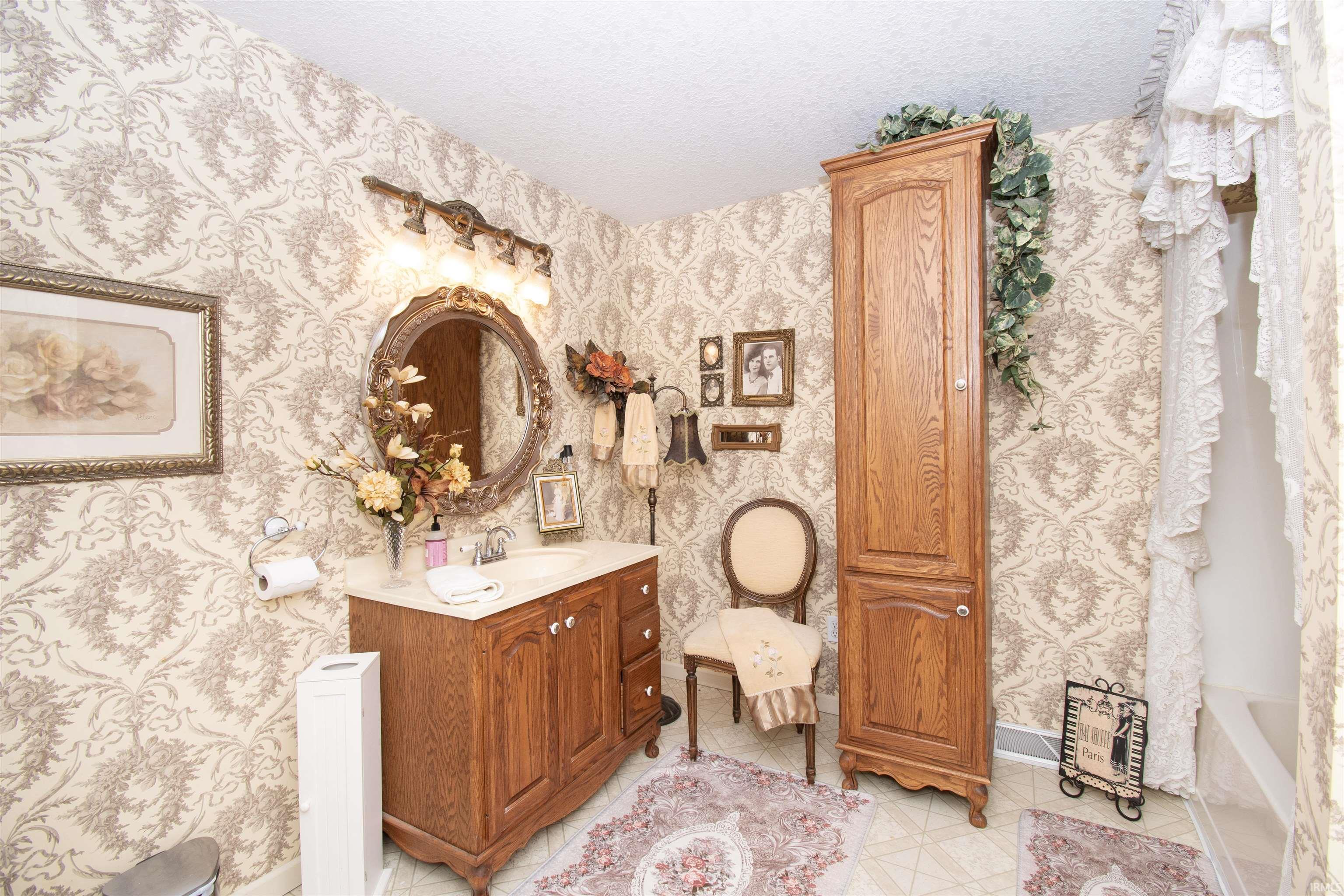 Full bath featuring vanity, a textured ceiling, and light tile patterned floors