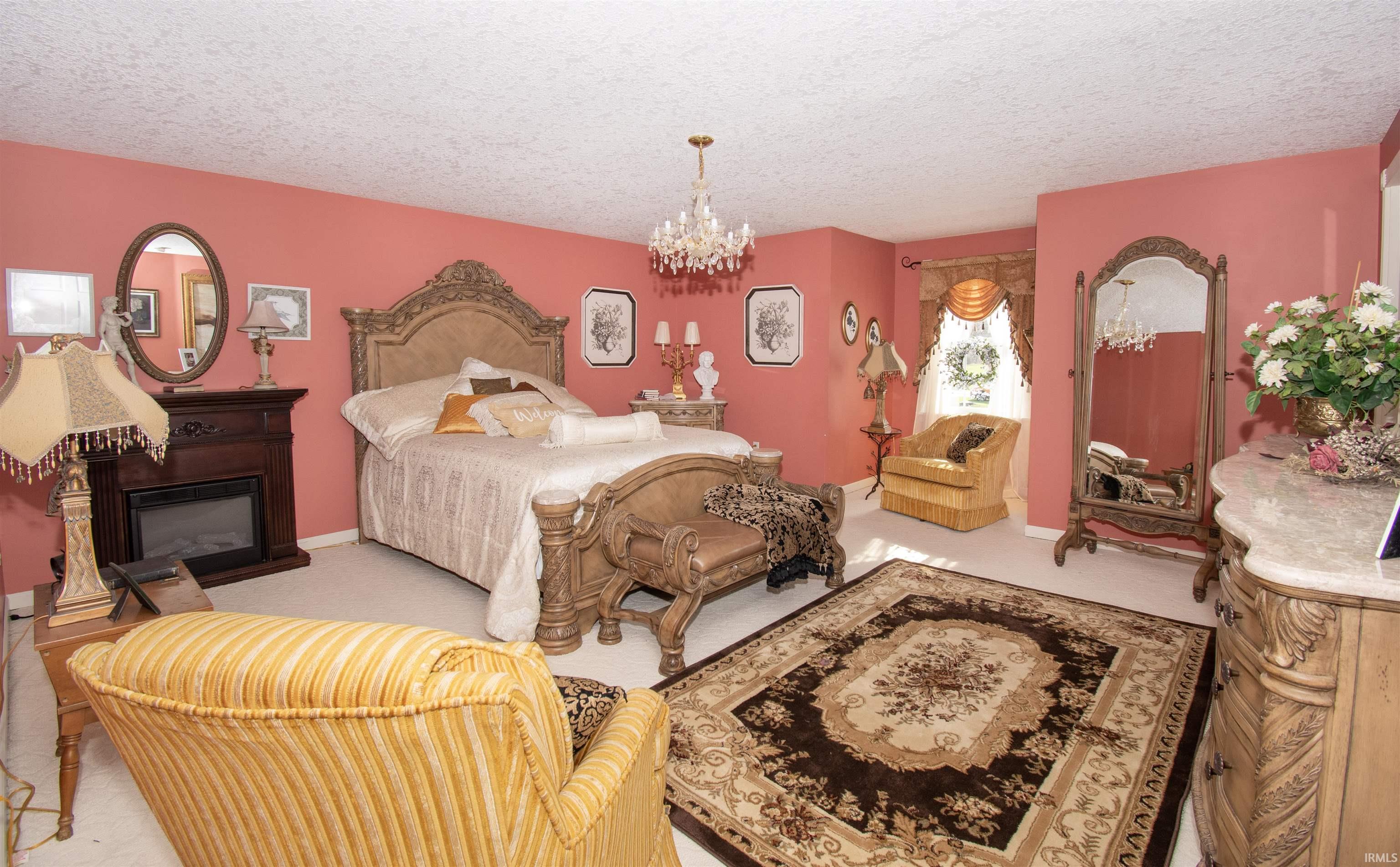 Bedroom with a chandelier, a glass covered fireplace, and a textured ceiling