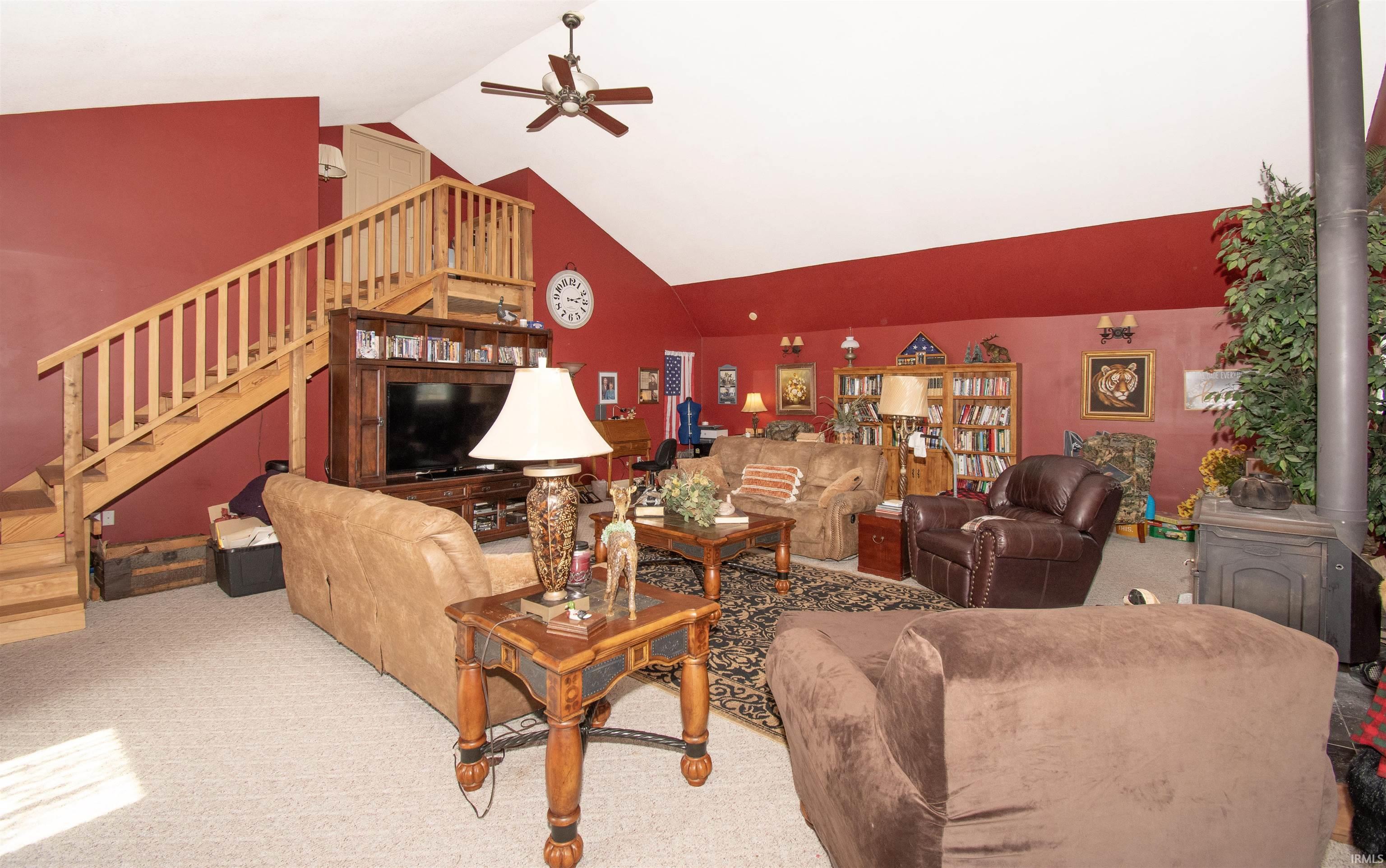 Carpeted living area featuring ceiling fan and a high ceiling