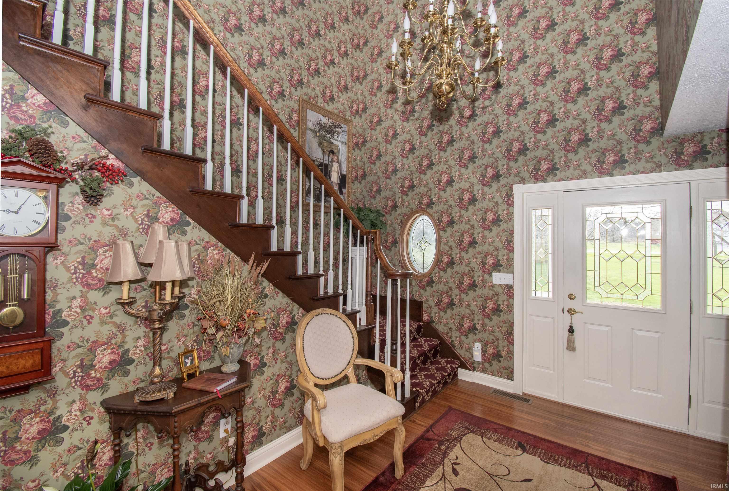 Foyer featuring wood finished floors, hanging lights, and wallpapered walls