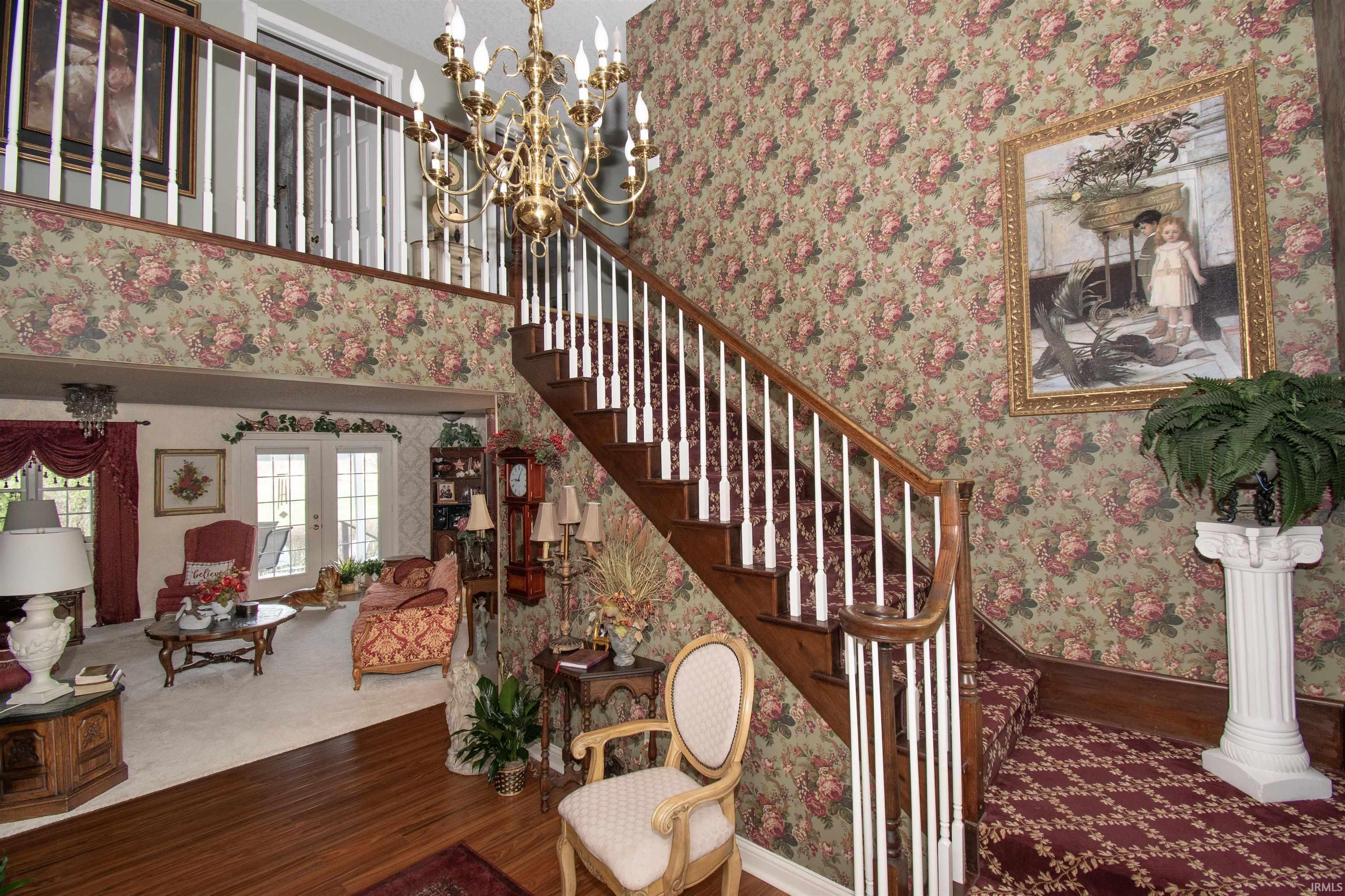 Stairs featuring wallpapered walls, french doors, hanging lights, wood finished floors, and a high ceiling