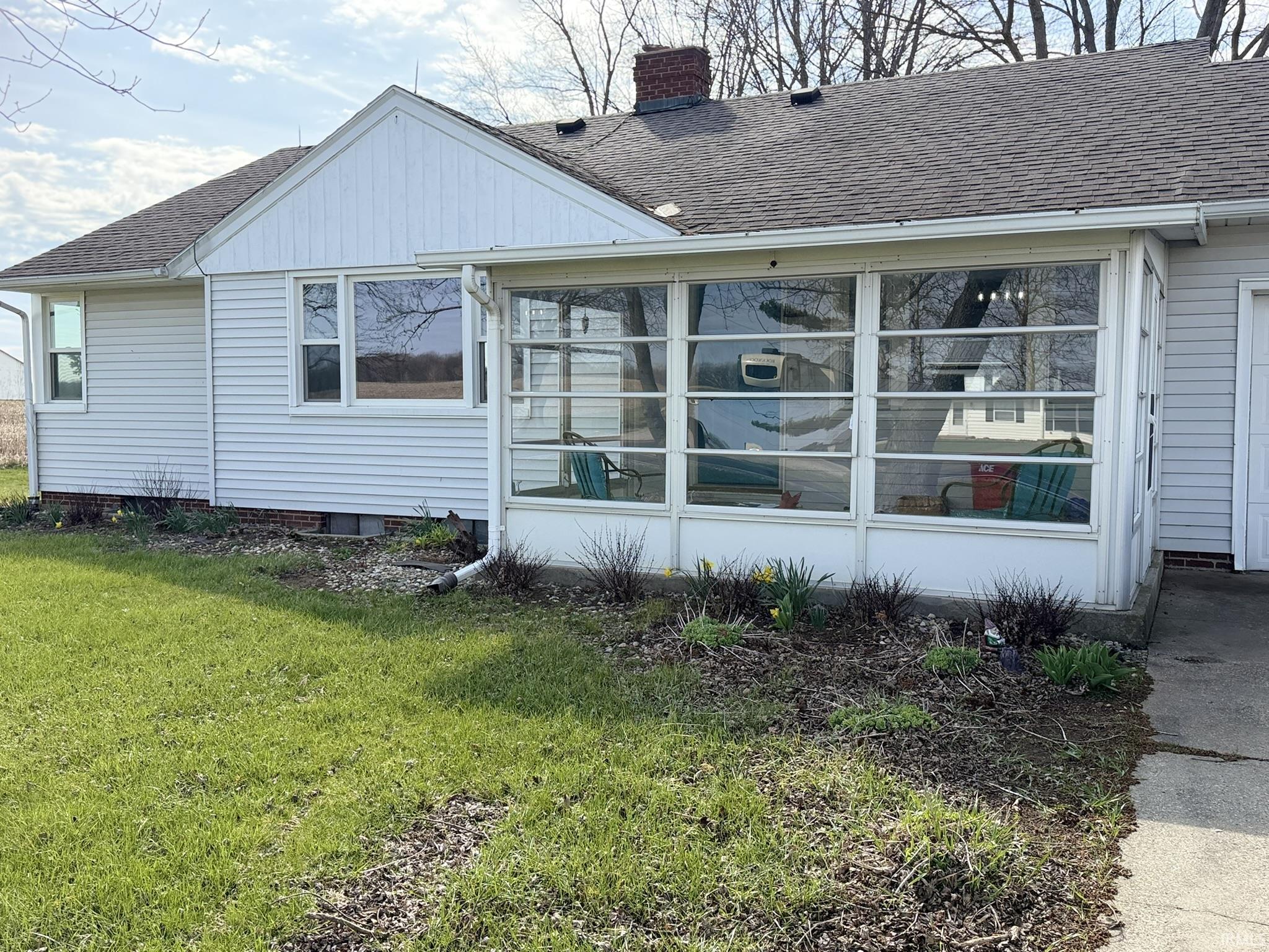View of side of property with a shingled roof, a chimney, and a yard