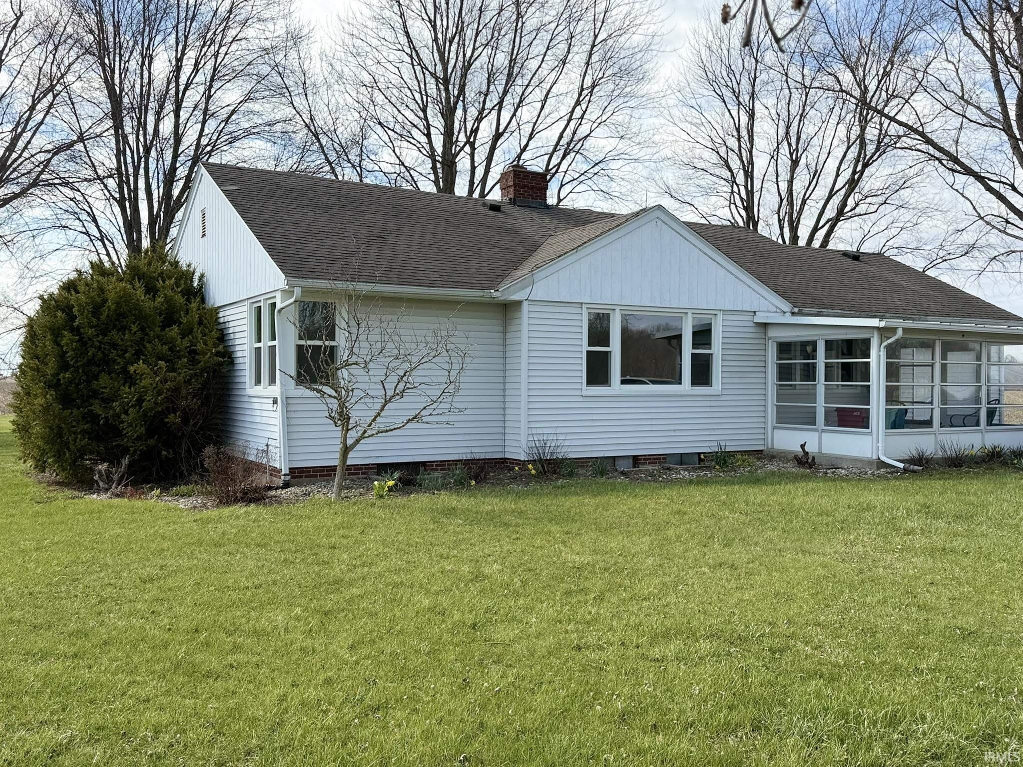 View of property exterior featuring a yard, a chimney, a sunroom, and a shingled roof