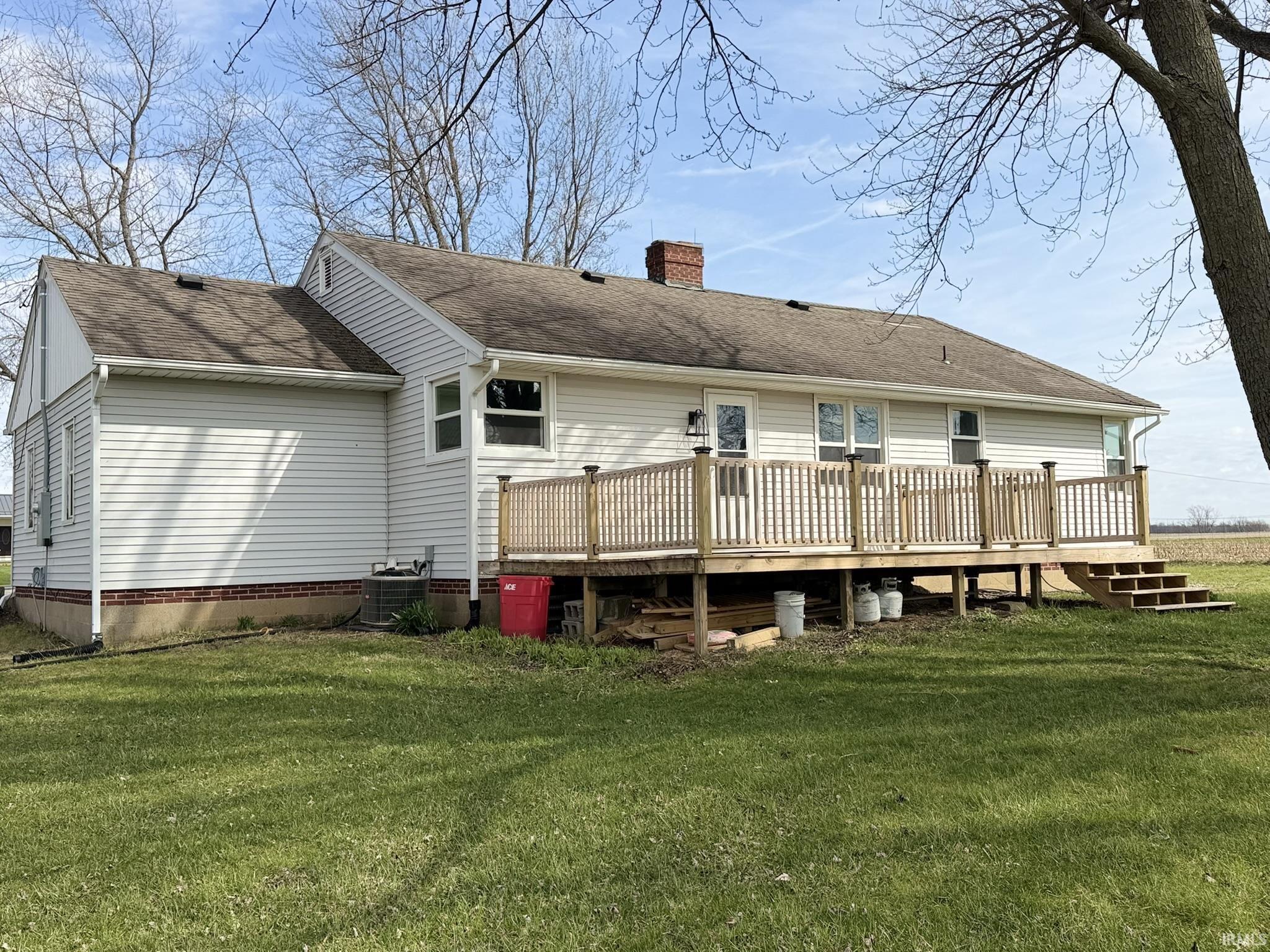 Rear view of house with a lawn, a deck, and a chimney