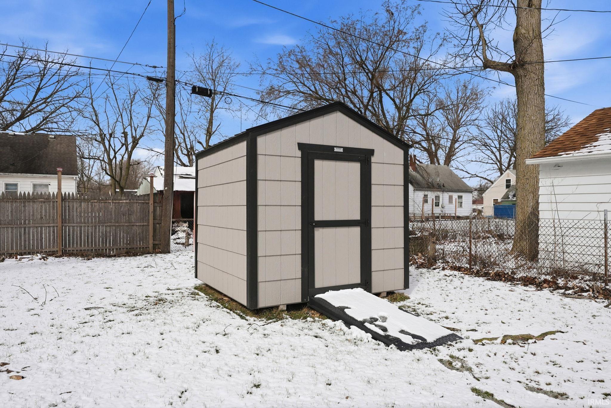 Snow covered structure featuring a fenced backyard and a storage shed