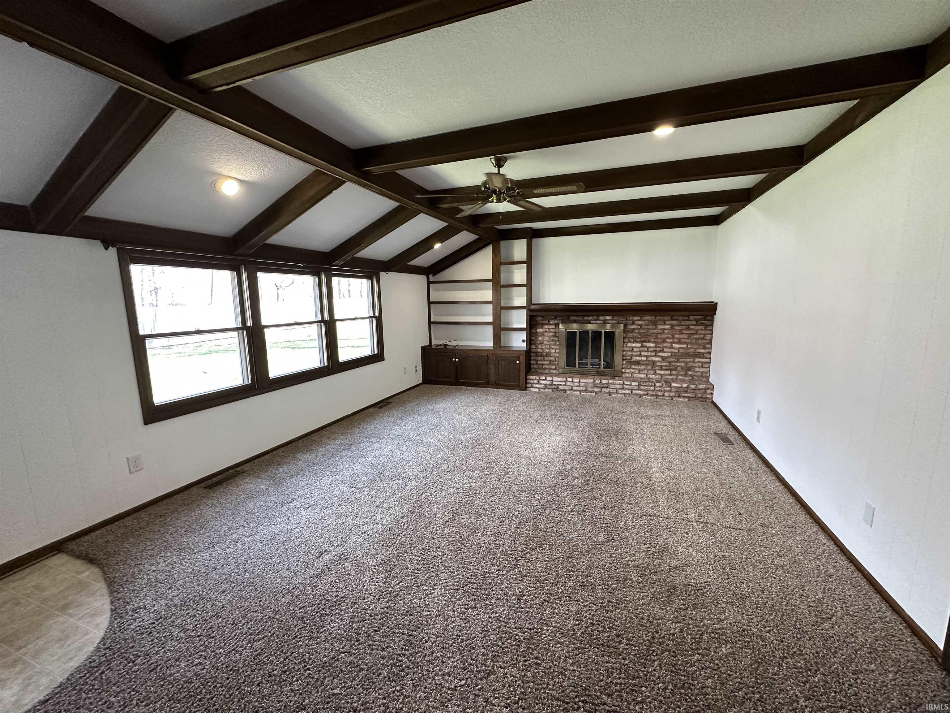 Ventless fireplace, ceiling fan, and beamed ceiling