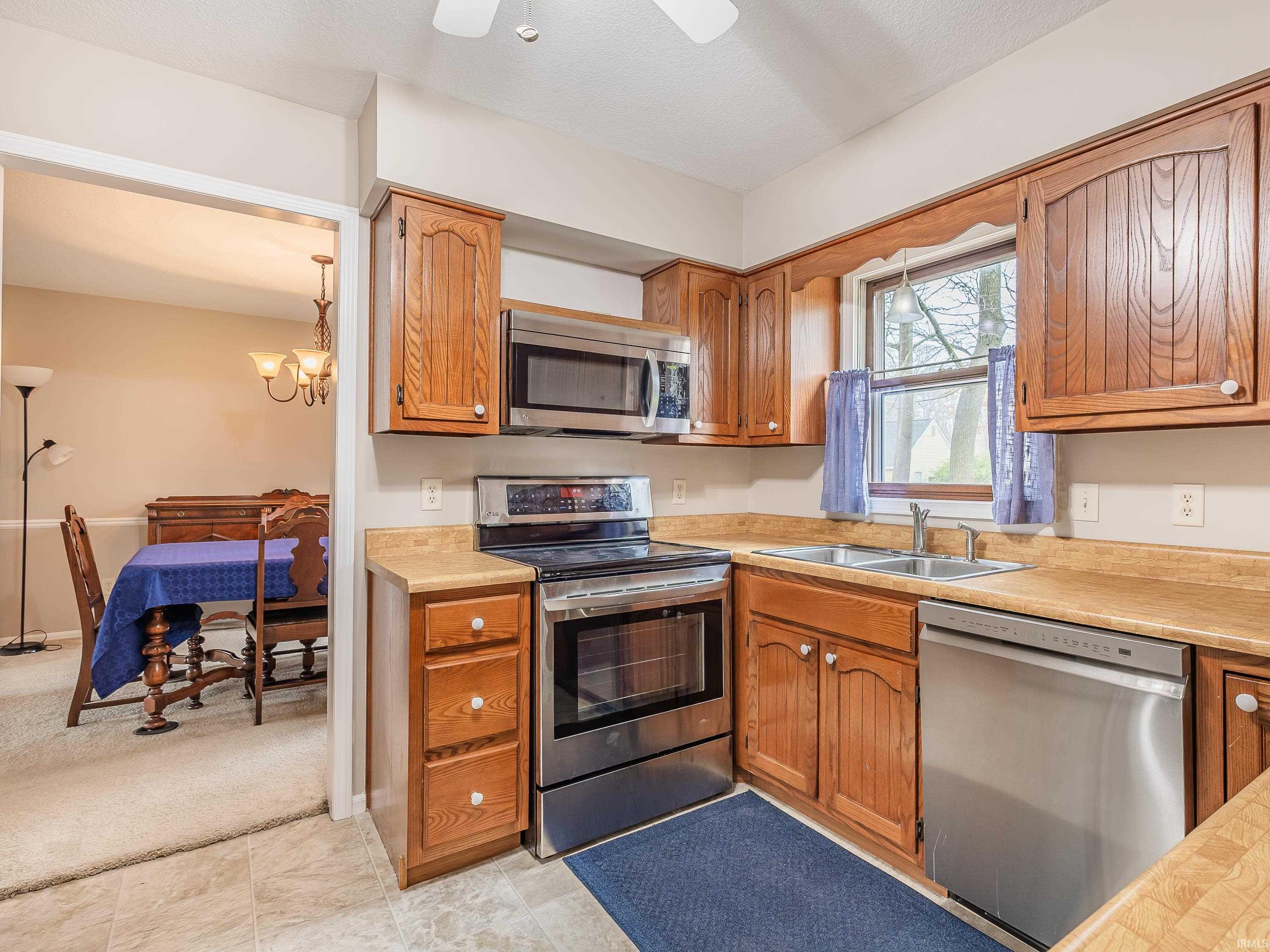 Kitchen with stainless steel appliances, light countertops, wood finish cabinets, and a ceiling fan