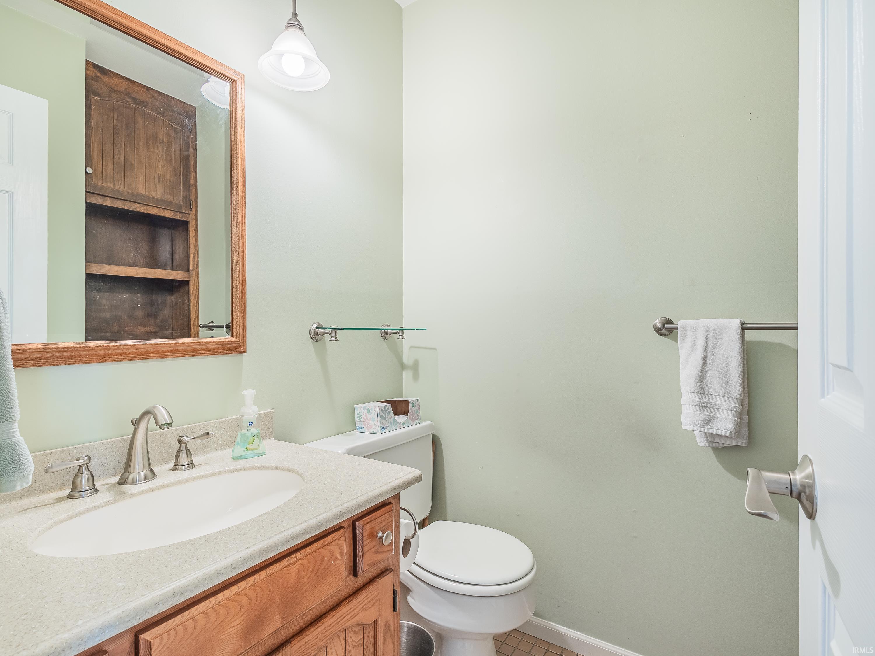 Half bath with vanity and light tile patterned flooring, and built-in shelves