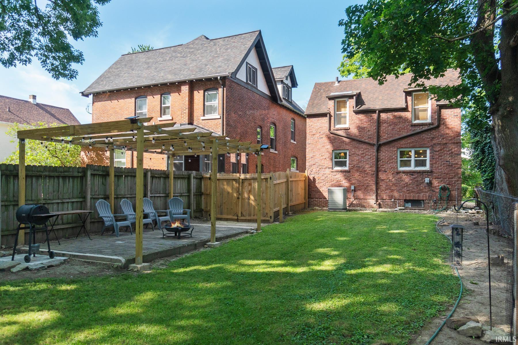 Back of property featuring a fenced backyard, brick siding, a pergola, a patio area, and a deck