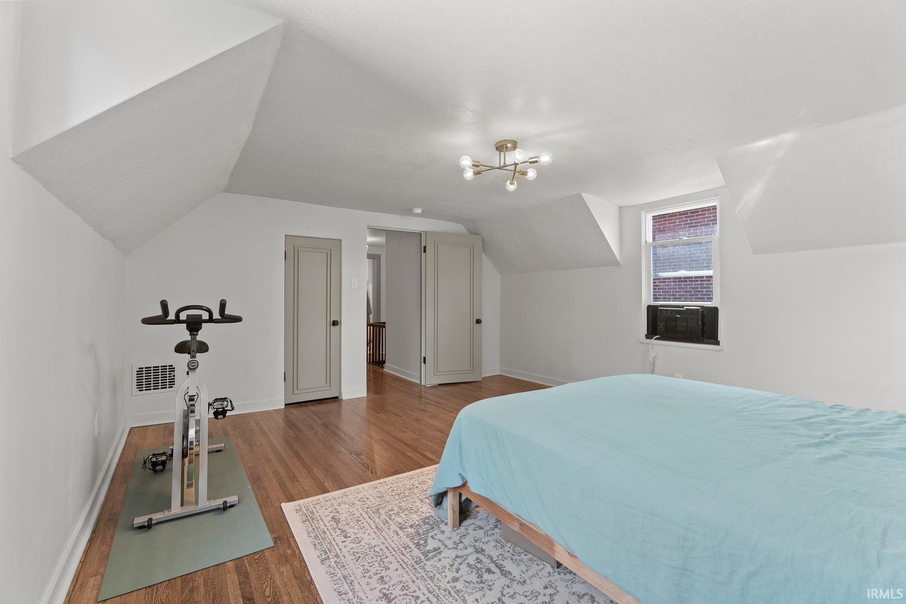 Bedroom featuring wood finished floors and vaulted ceiling