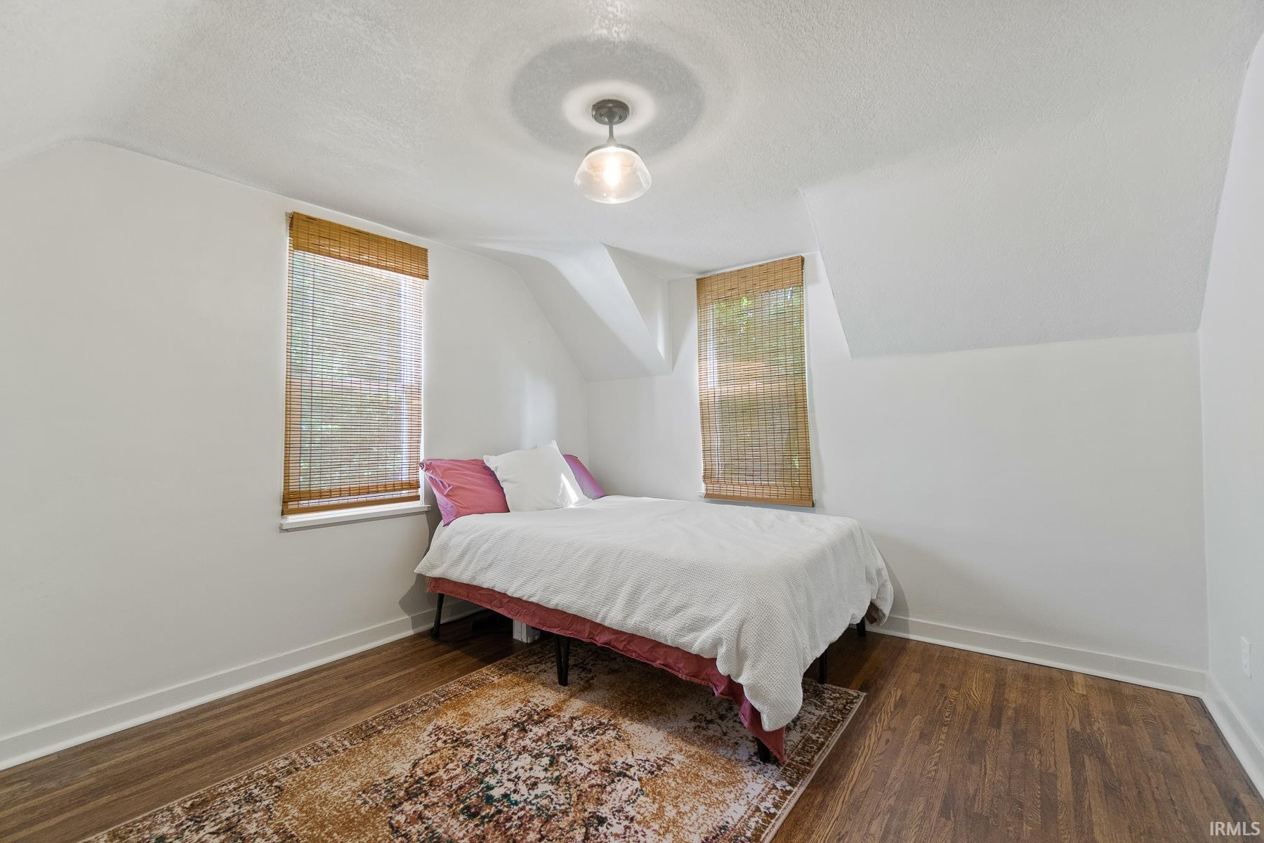 Bedroom featuring dark wood-style flooring and baseboards