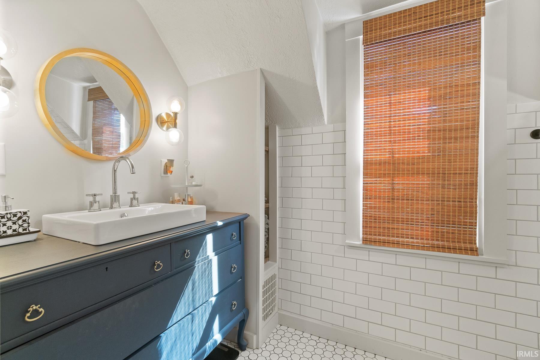 Bathroom with vanity, light tile patterned flooring, and tile walls