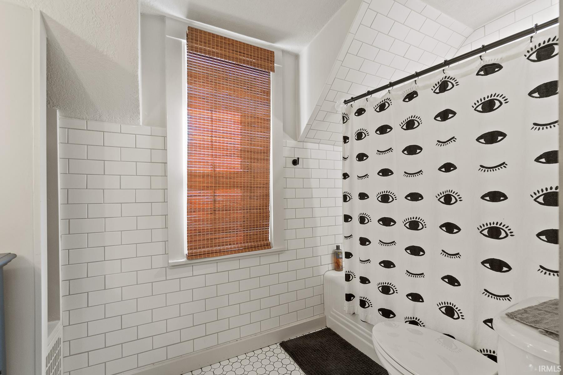 Bathroom featuring tile walls, a shower with curtain, and a textured wall