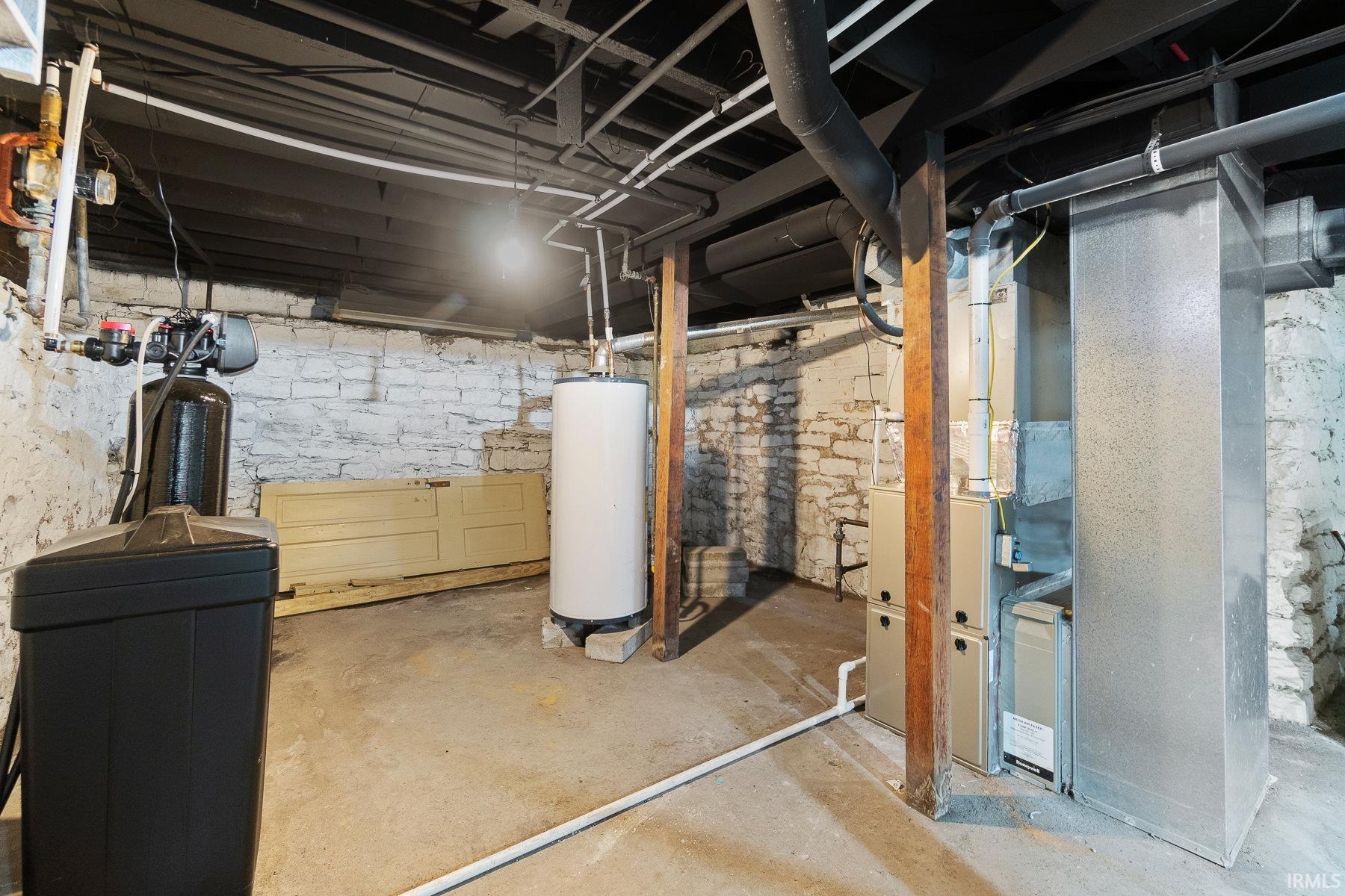 Unfinished basement with a water softener system, water heater, and heating unit