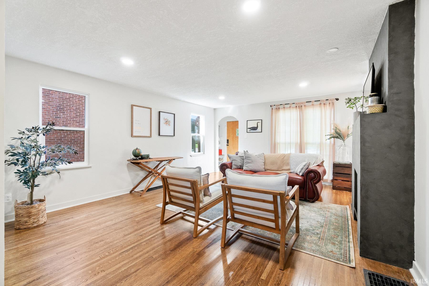 Living area with arched walkways, light wood finished floors, and a textured ceiling