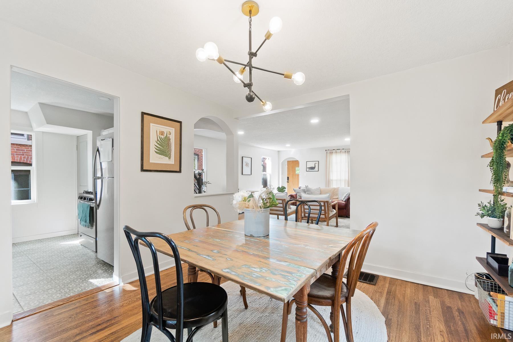 Dining space featuring arched walkways, hanging lights, and wood finished floors