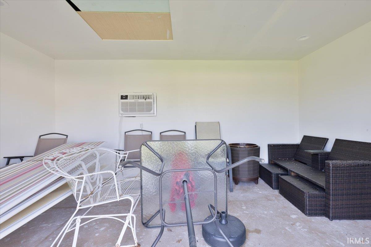 View of patio with outdoor lounge area and a wall unit AC