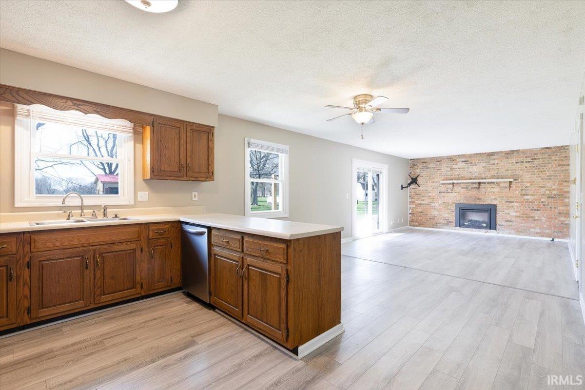 Kitchen featuring light countertops, brick wall, wood finish cabinets, a textured ceiling, and light wood-type flooring