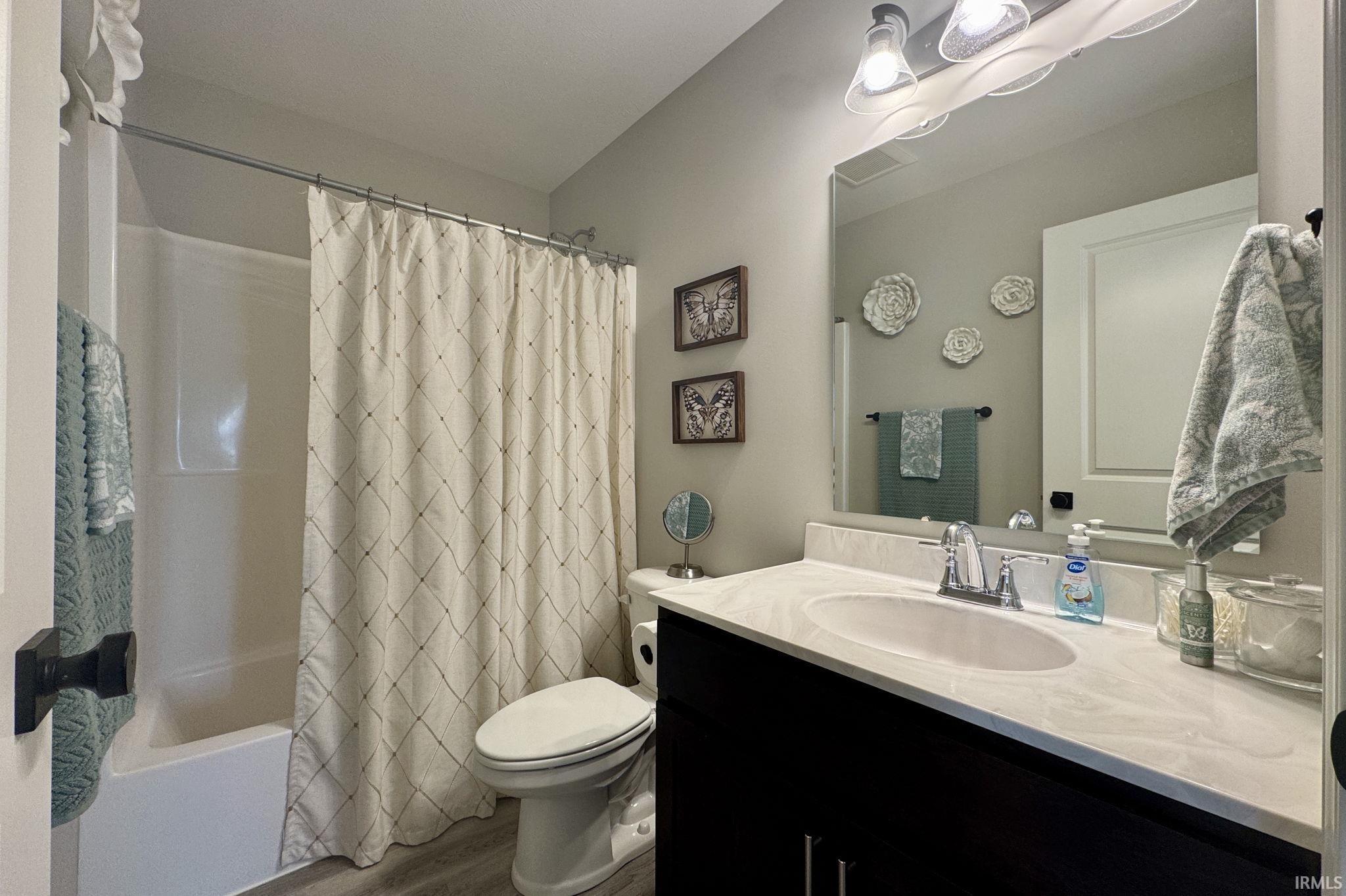 Full bath with vanity, shower / bath combo, and wood finished floors