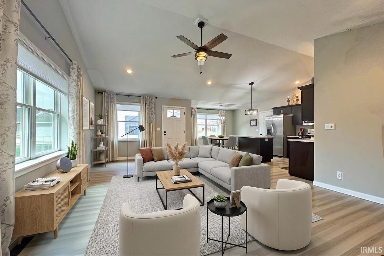 Vaulted ceiling with a ceiling fan, recessed lighting, wood-finish flooring, and a kitchen featuring dark cabinetry and stainless steel appliances