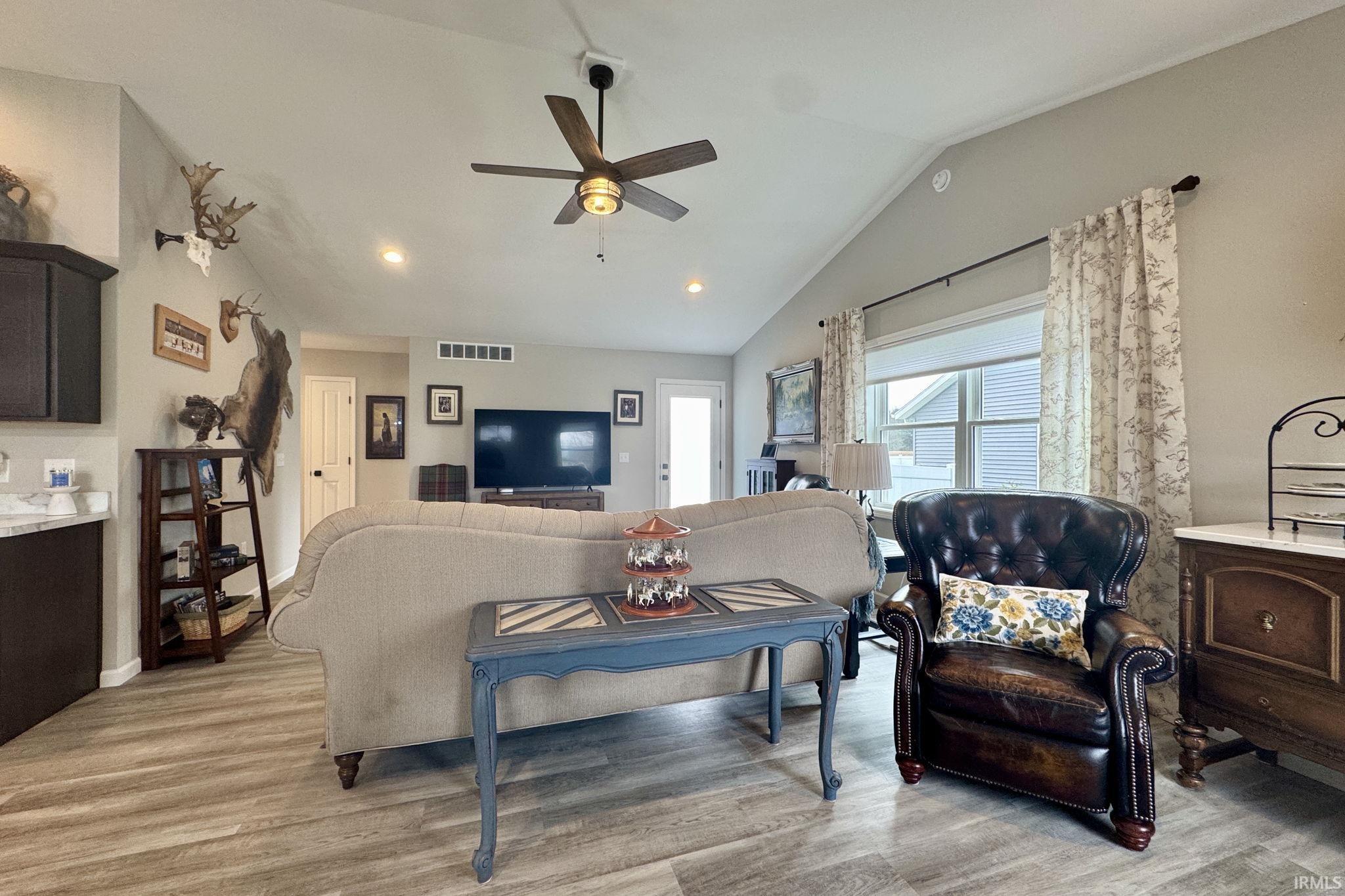 Living area with light wood-type flooring, ceiling fan, vaulted ceiling, and recessed lighting