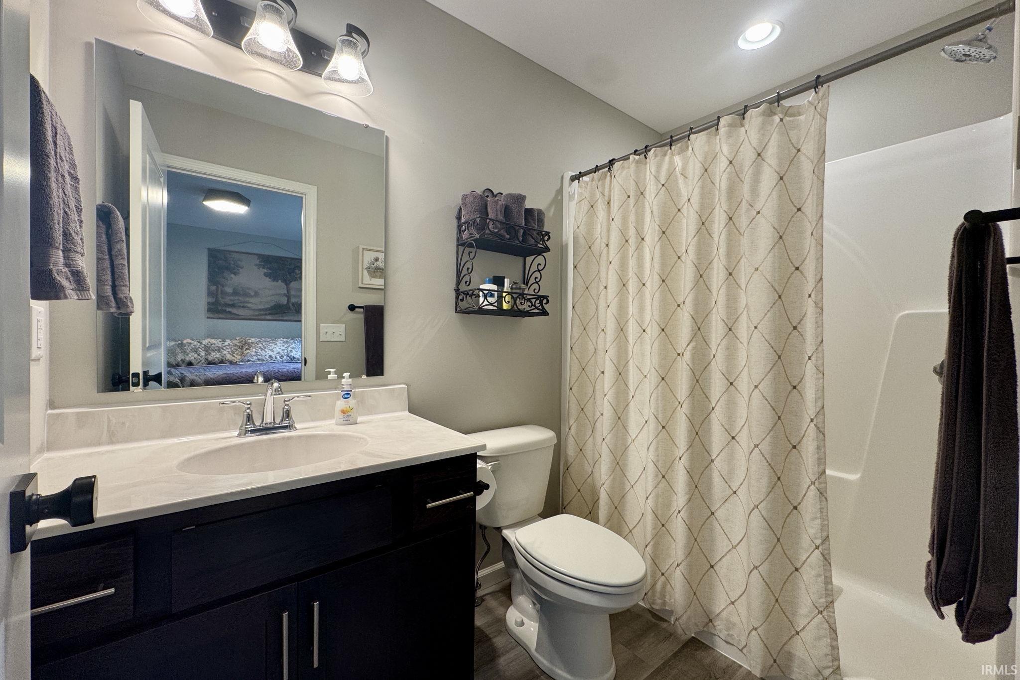 Ensuite bathroom with vanity, wood finished floors, and shower / bath combo