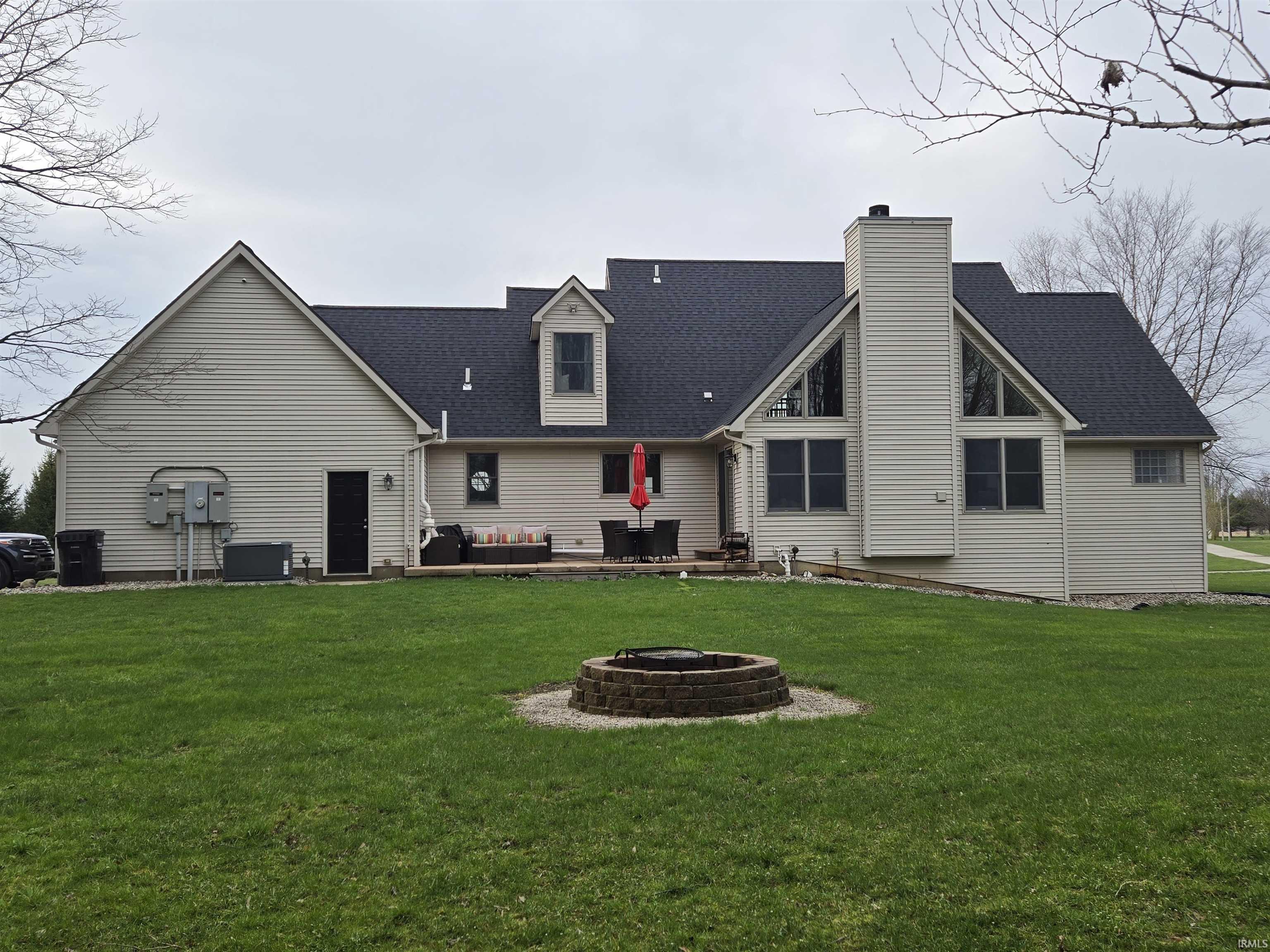 Back of house featuring a patio area, a shingled roof, a fire pit, a lawn, and a chimney
