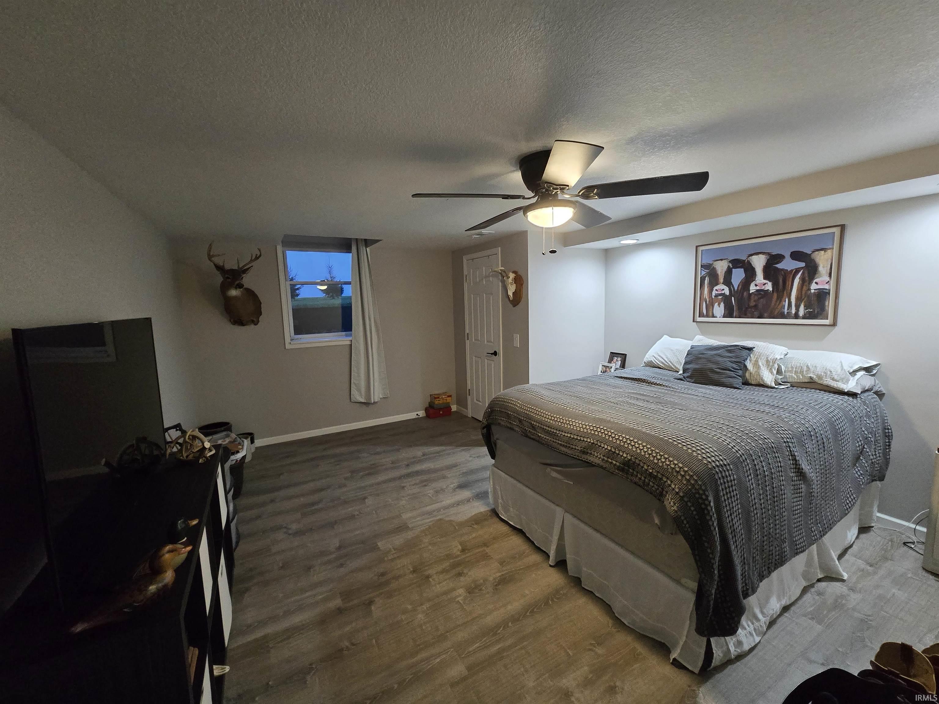Bedroom featuring wood finished floors, a textured ceiling, and a ceiling fan