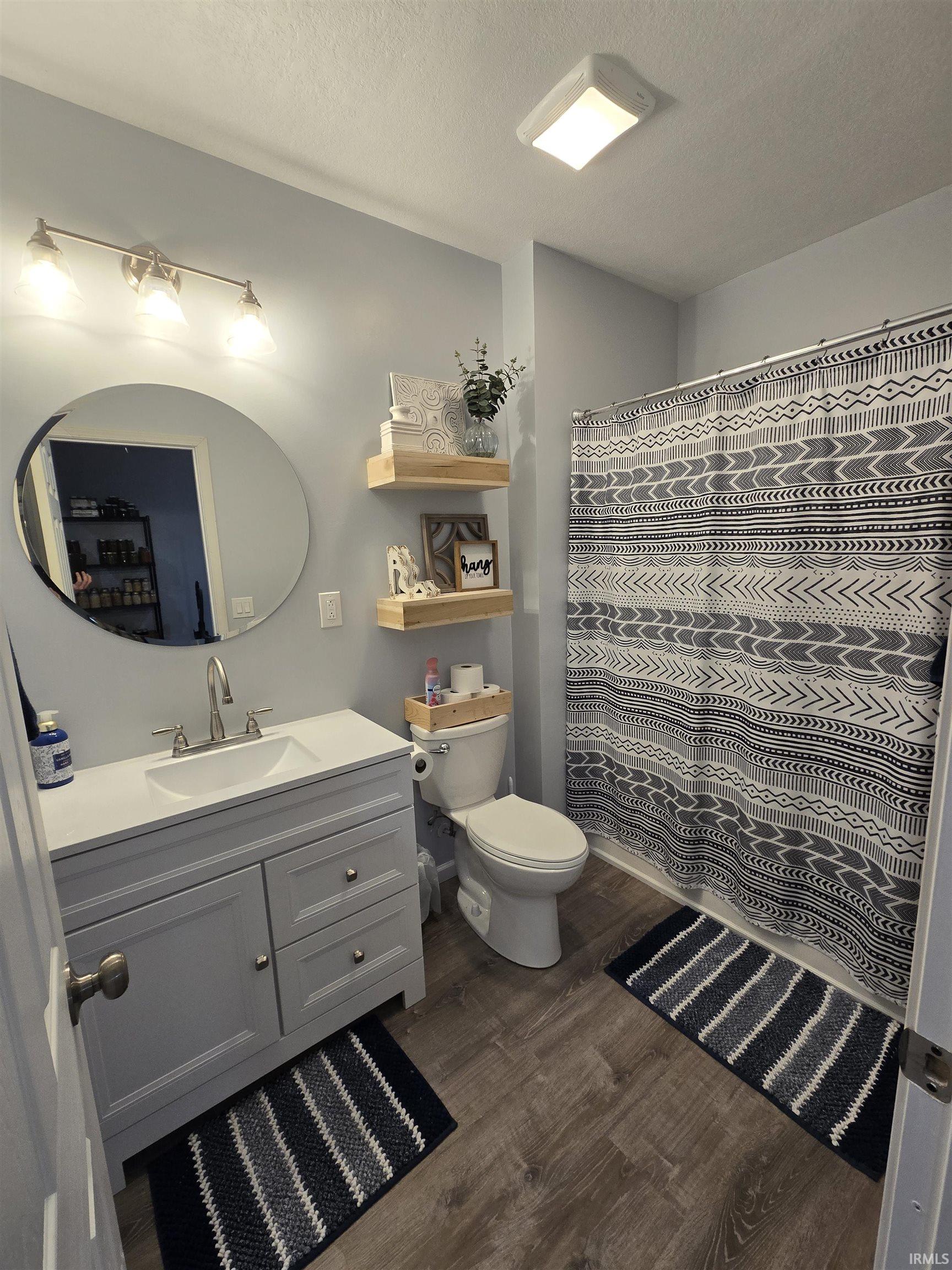 Full bath featuring vanity, curtained shower, dark wood-style floors, and a textured ceiling