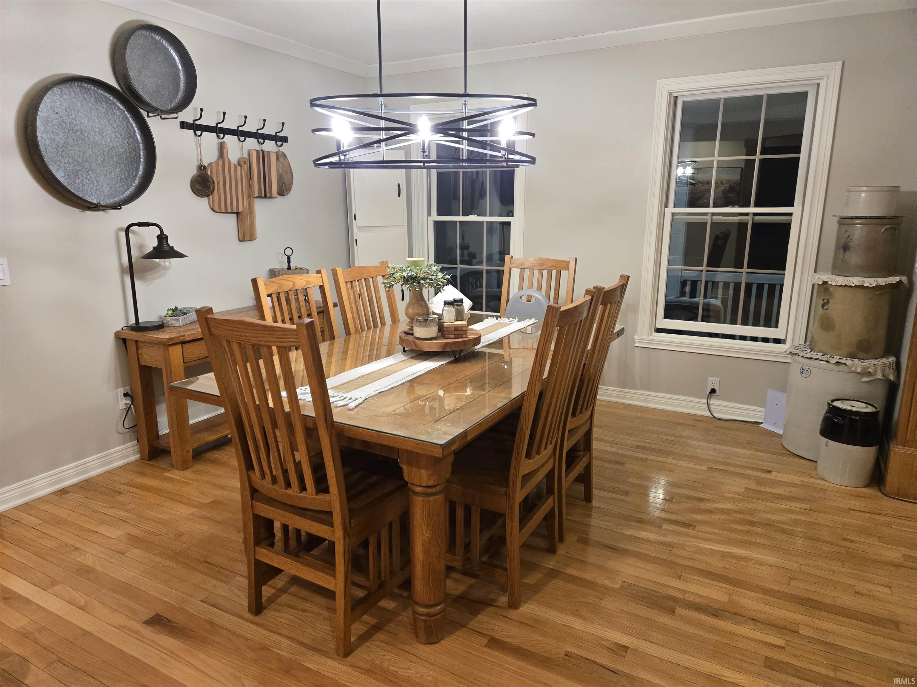 Dining space with hardwood / wood-style flooring, hanging lights, and ornamental molding
