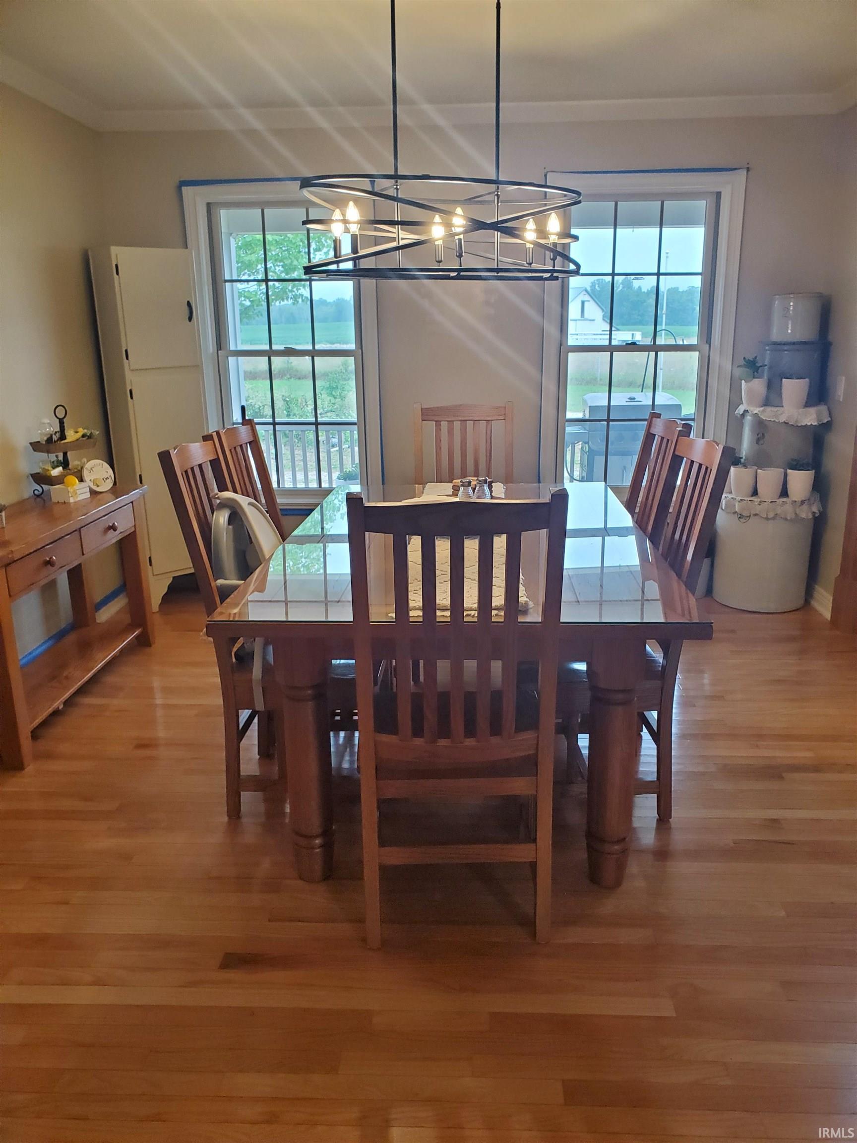 Dining space featuring wood finished floors, crown molding, a chandelier, and plenty of natural light