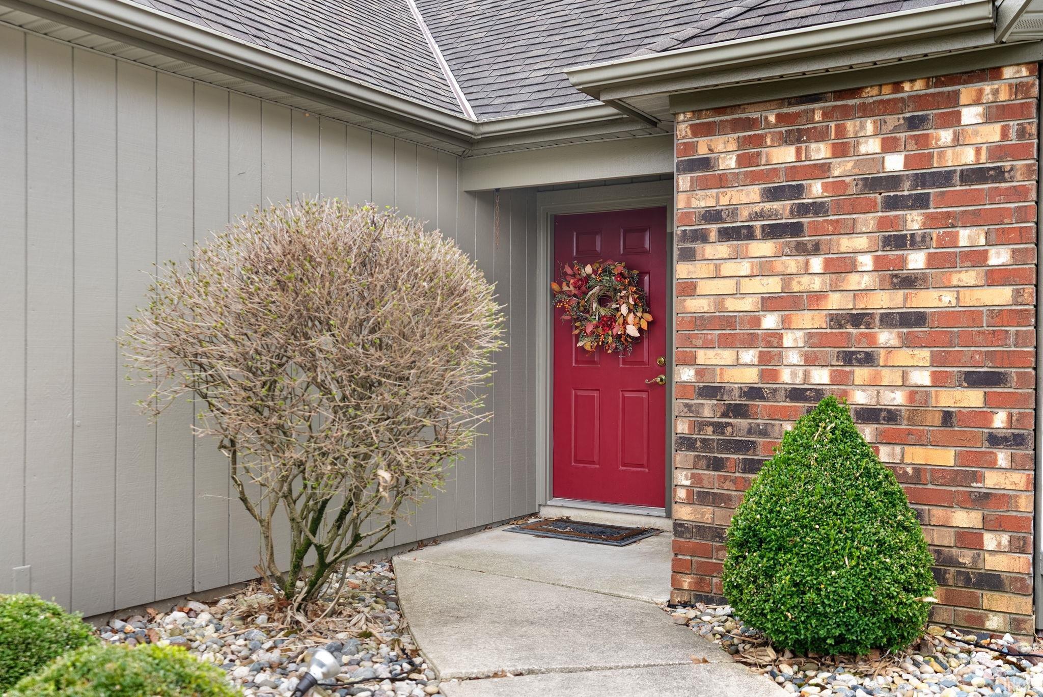 Doorway to property featuring a shingled roof and brick siding