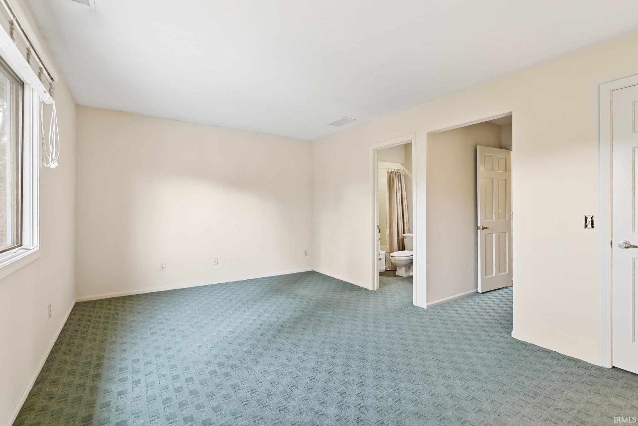 Unfurnished bedroom with carpet floors and ensuite bathroom
